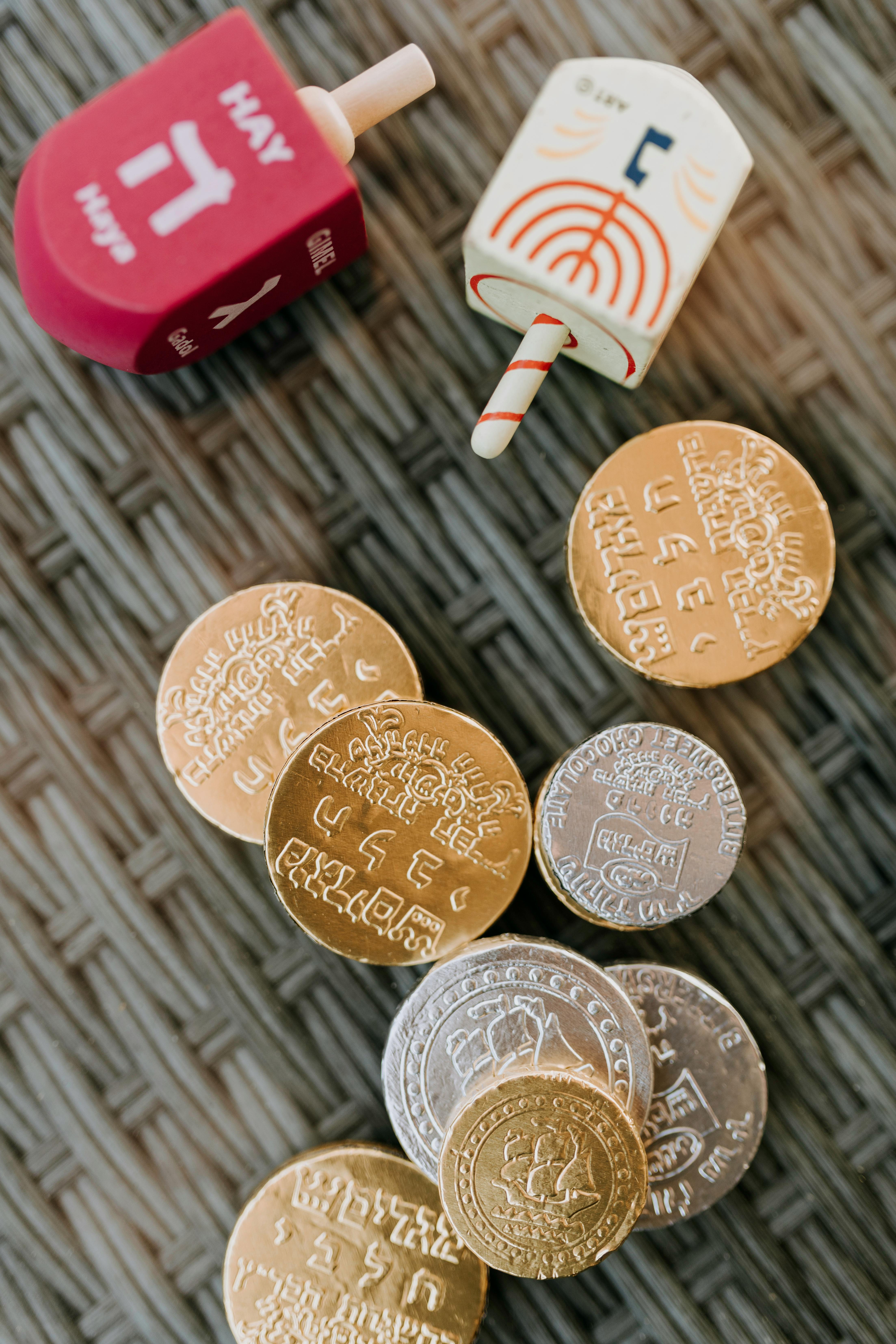 close up photo of dreidel spinners beside gold coins