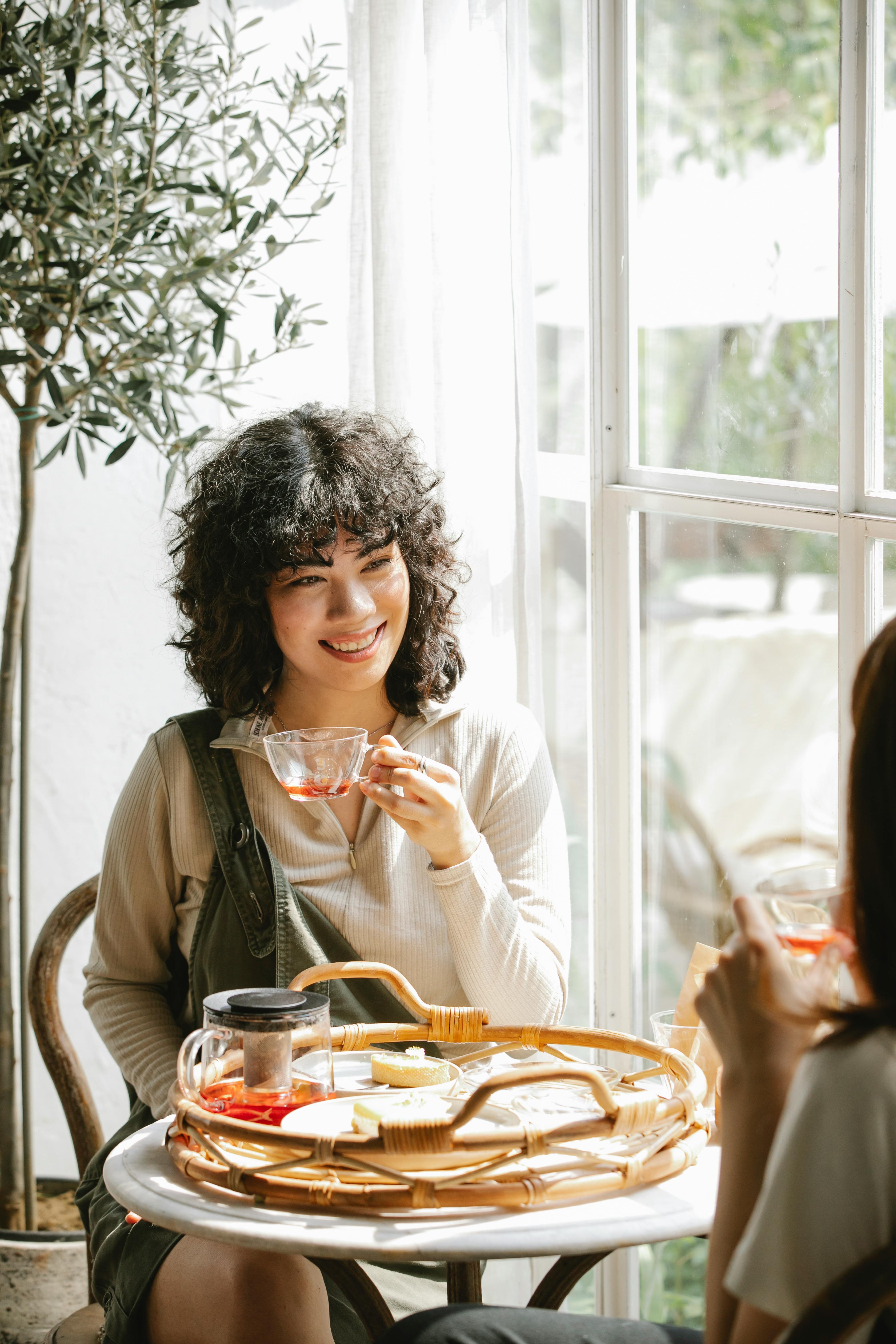 smiling ethnic woman having breakfast with friend