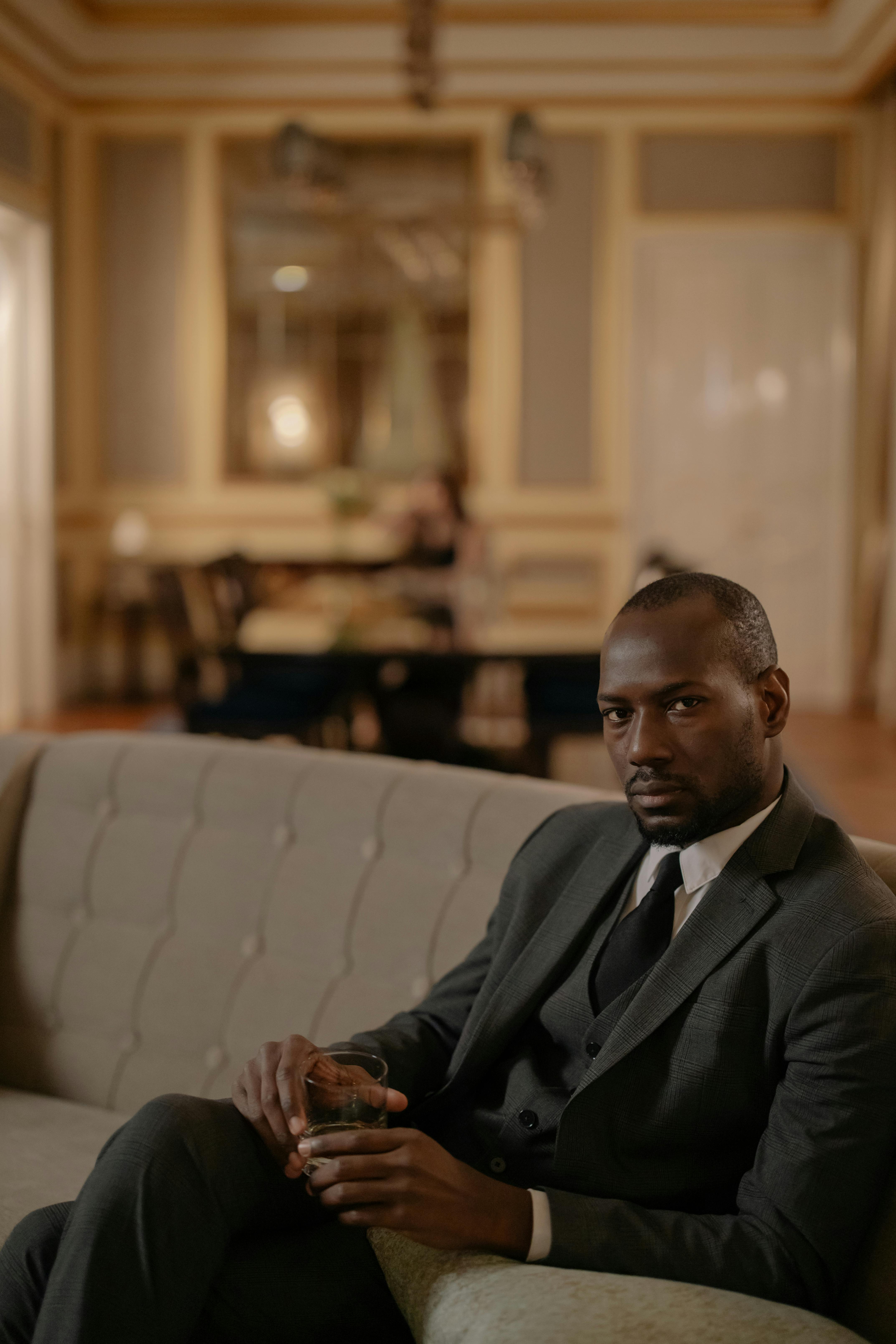 man in black suit sitting on couch