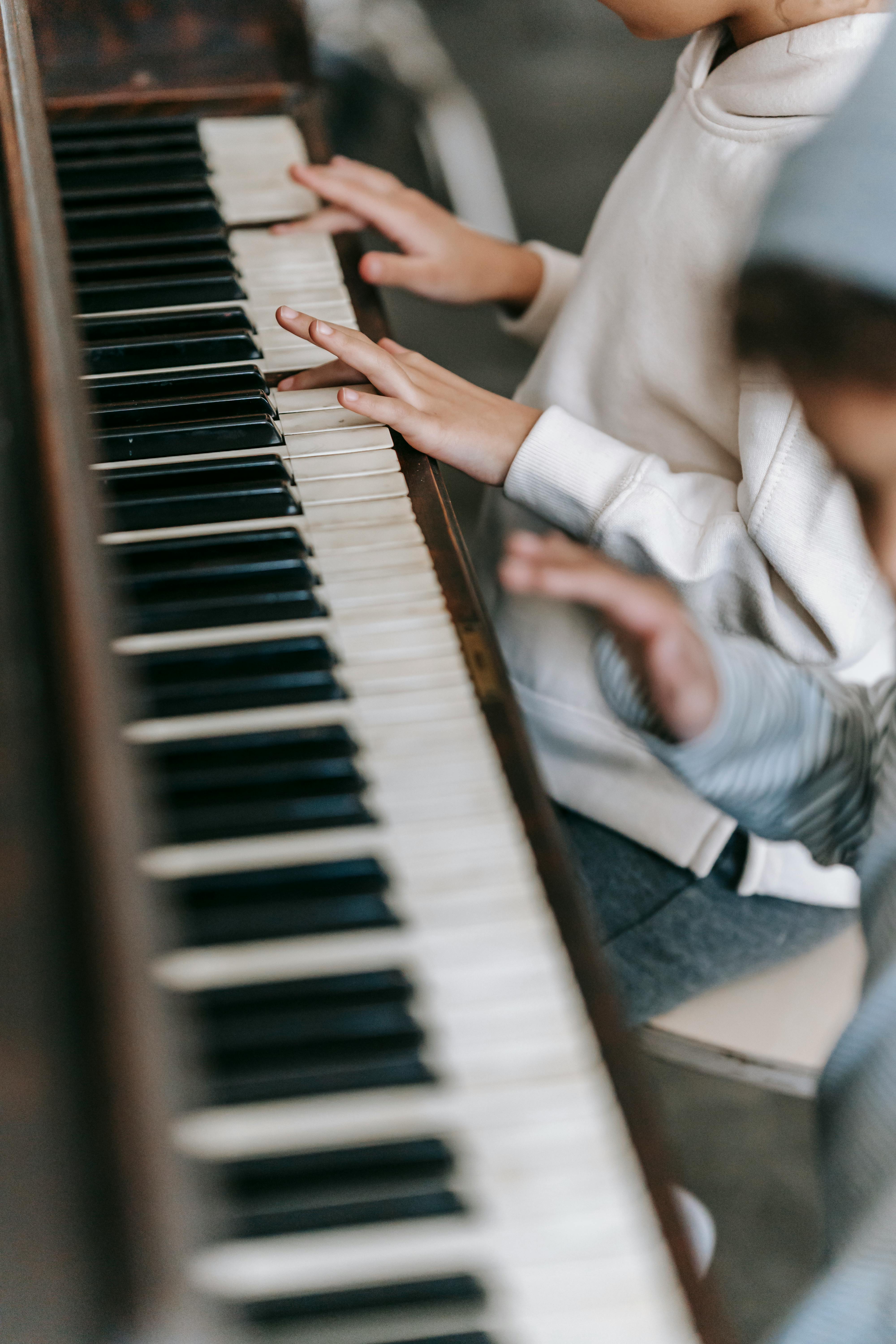 anonymous ethnic children playing piano in room