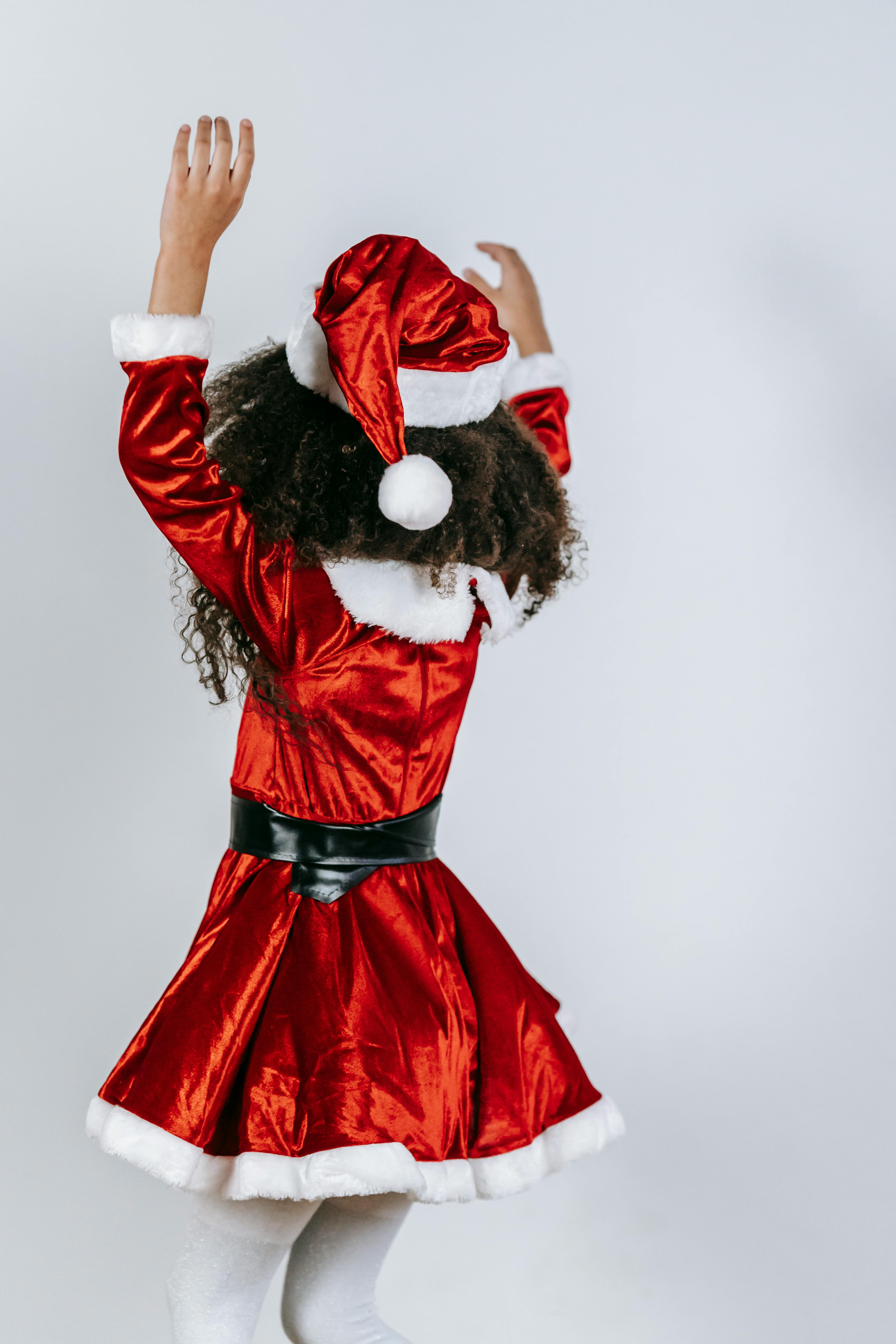 faceless black girl in santa costume spinning around on light background