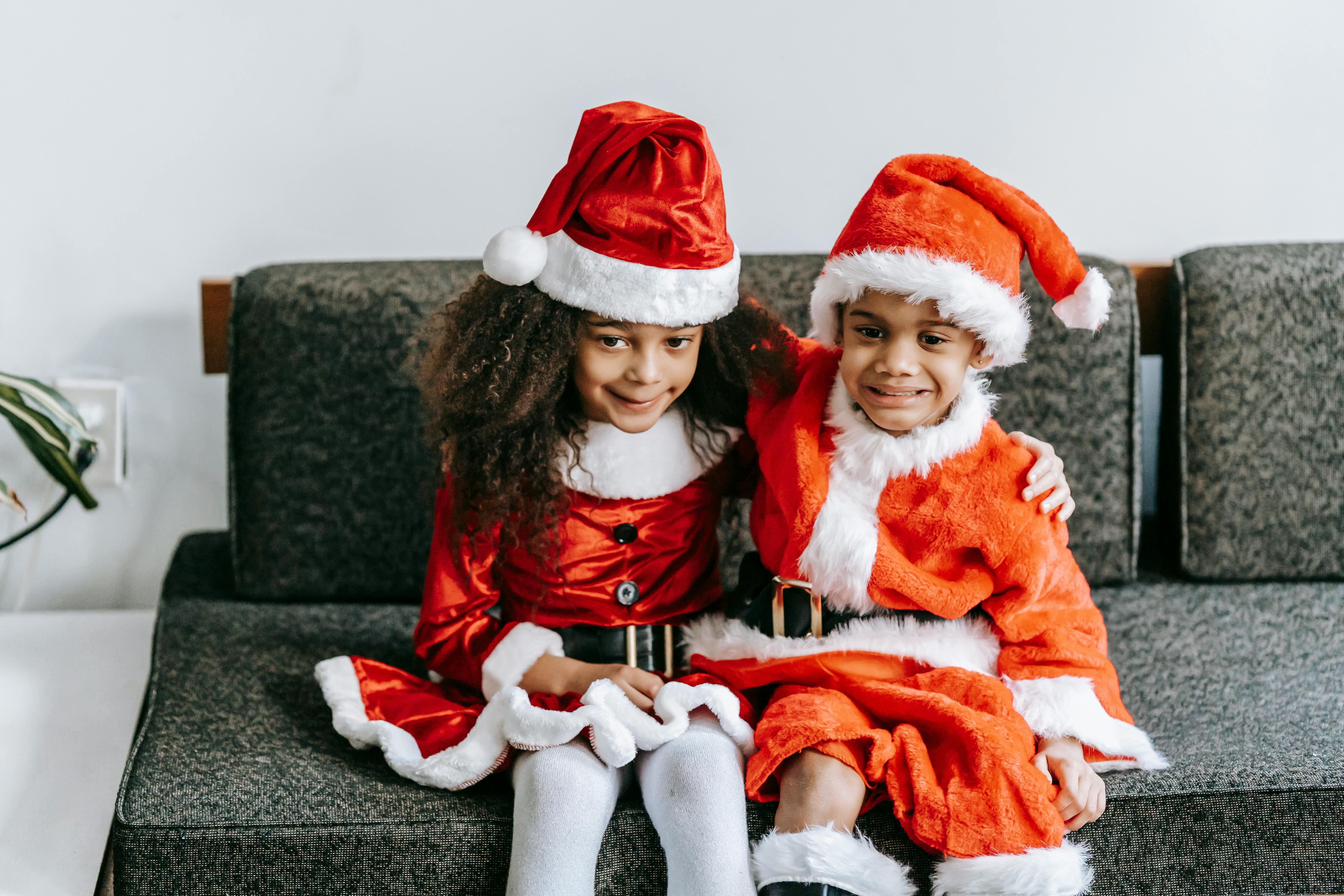 smiling ethnic siblings embracing during new year holiday on couch