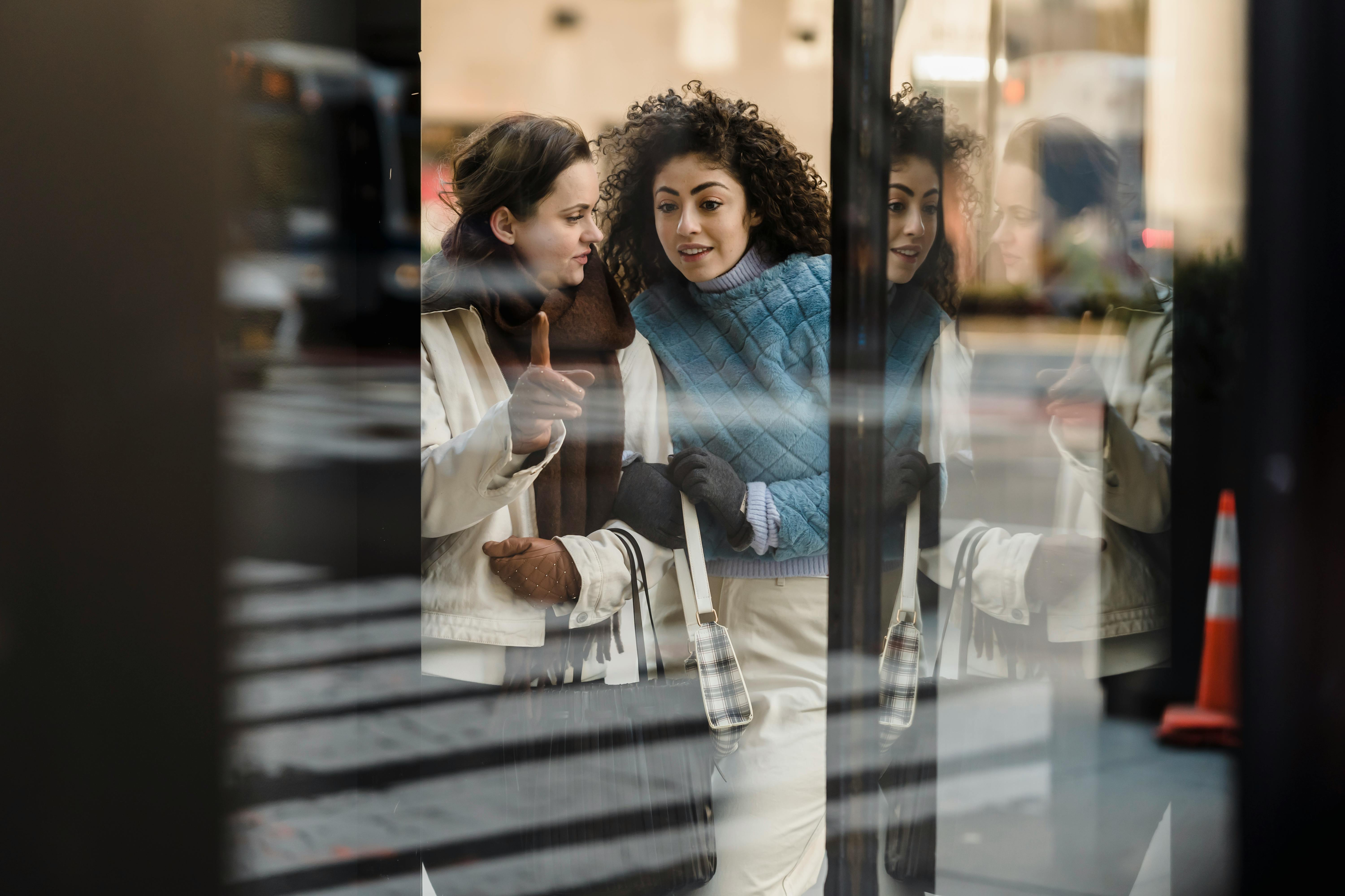 through glass of content multiethnic women standing near showcase