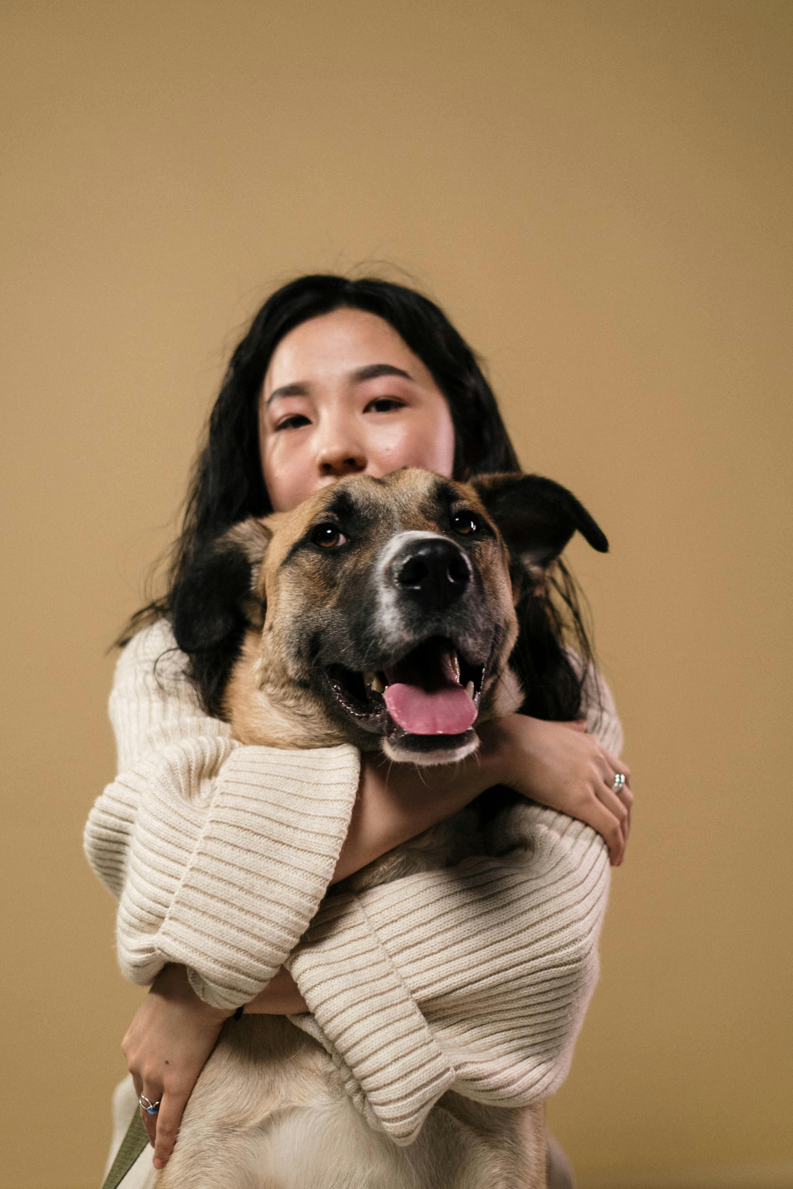 woman in white knitted sweater hugging brown dog