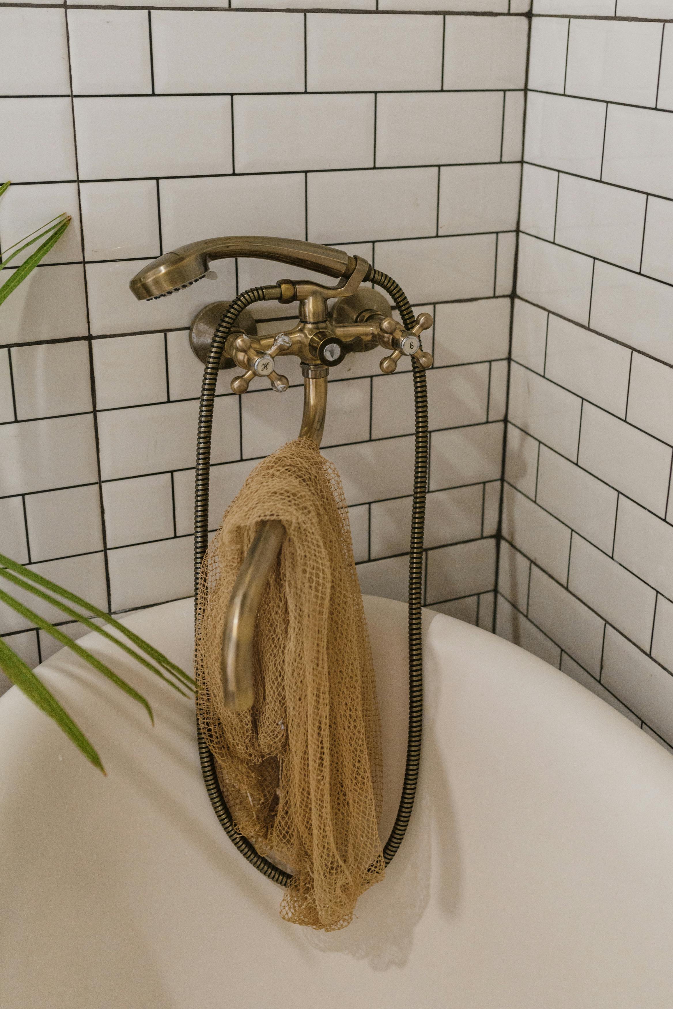 a bronze shower head and faucet over a bathtub