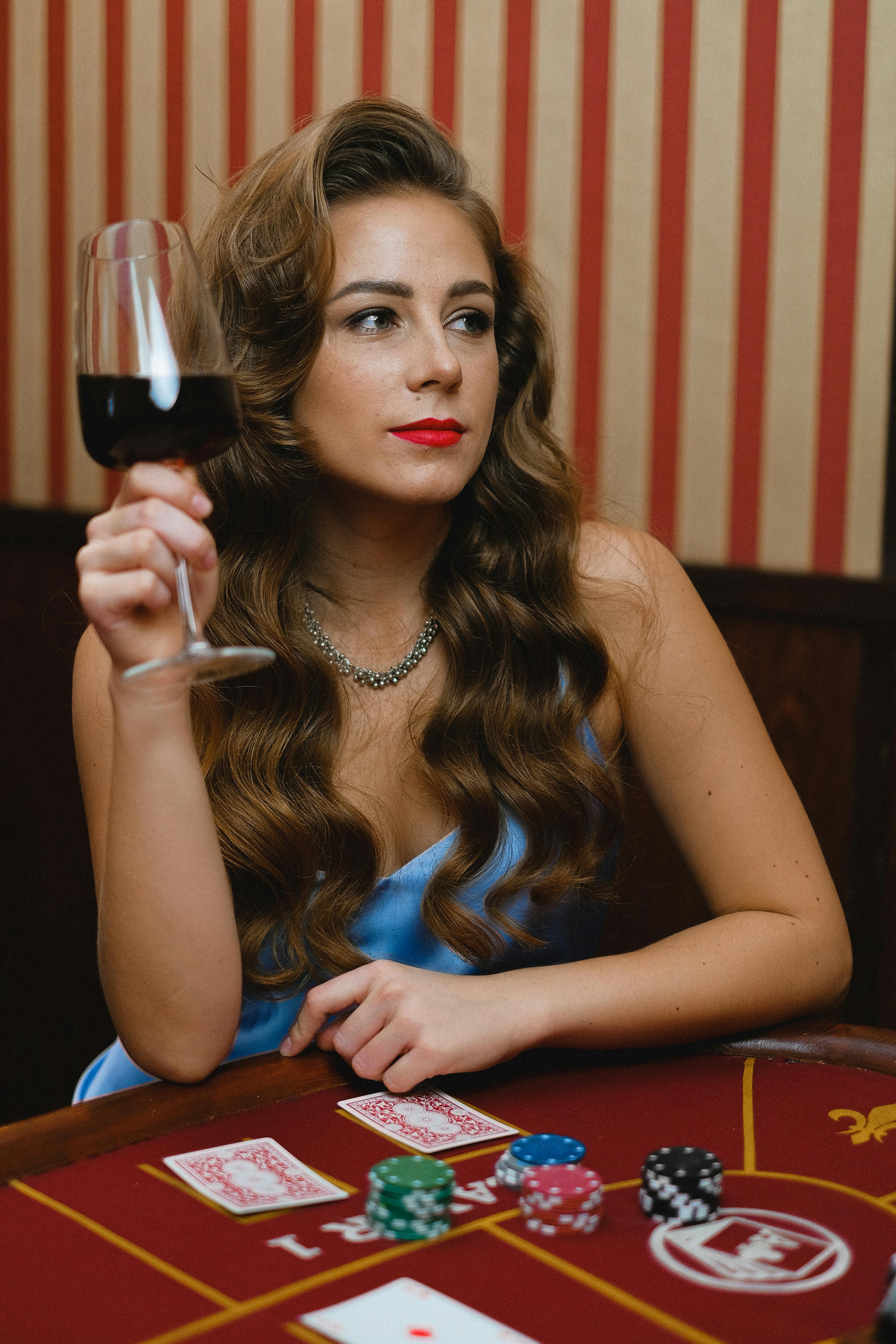 a woman holding a glass of wine while playing poker