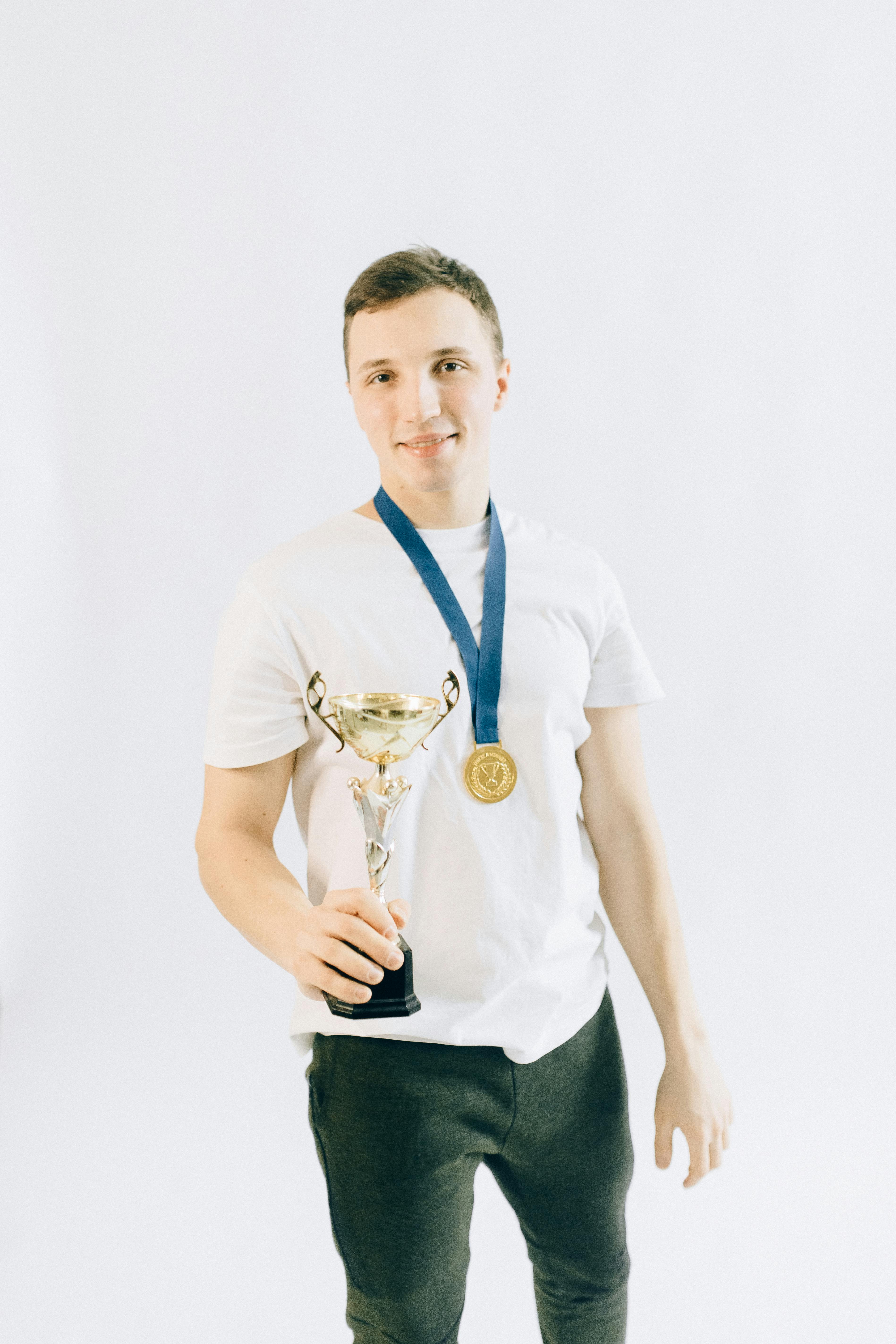 a man with a medal holding a trophy