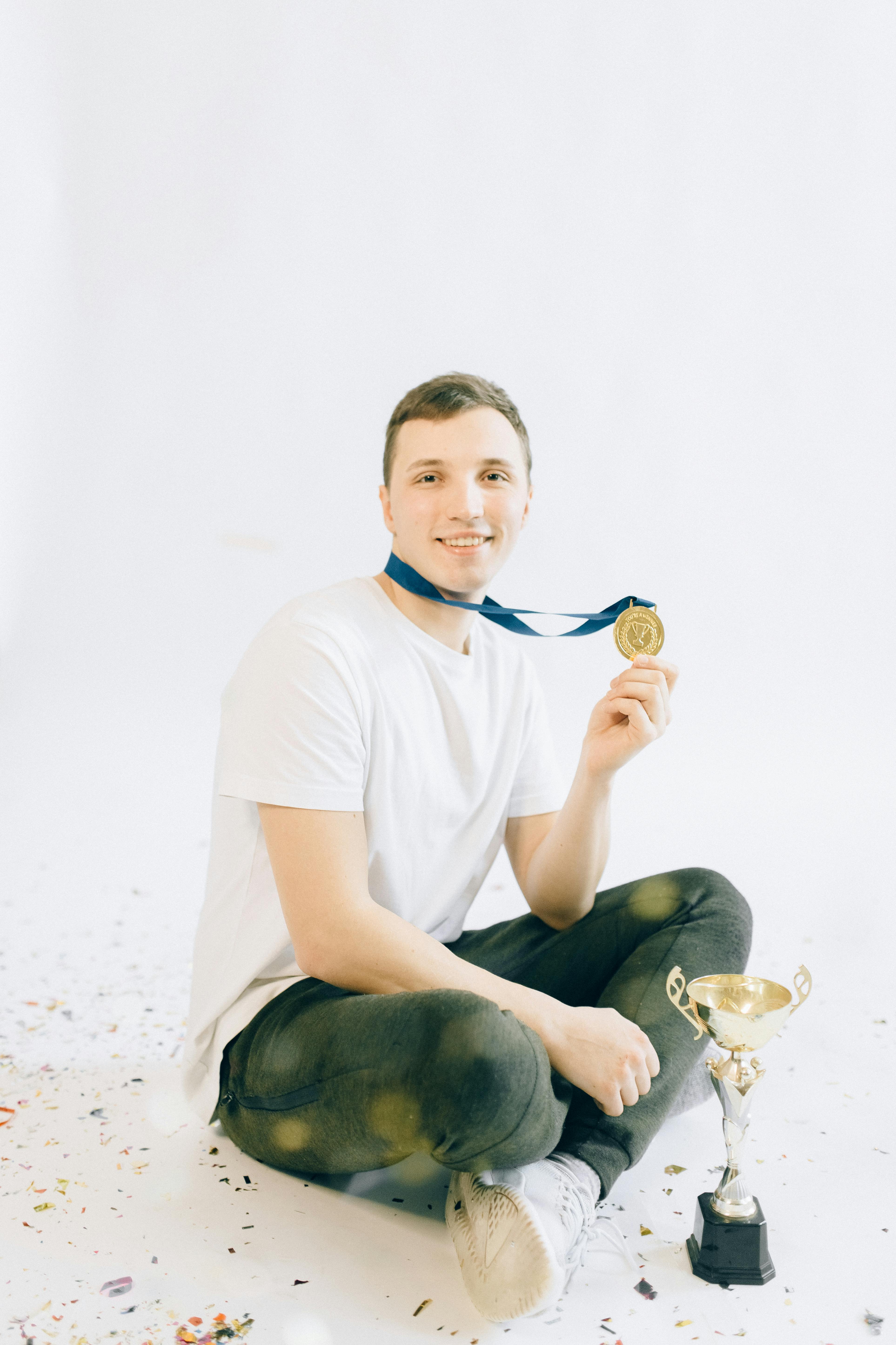 man in white crew neck t shirt and black pants sitting on white sand