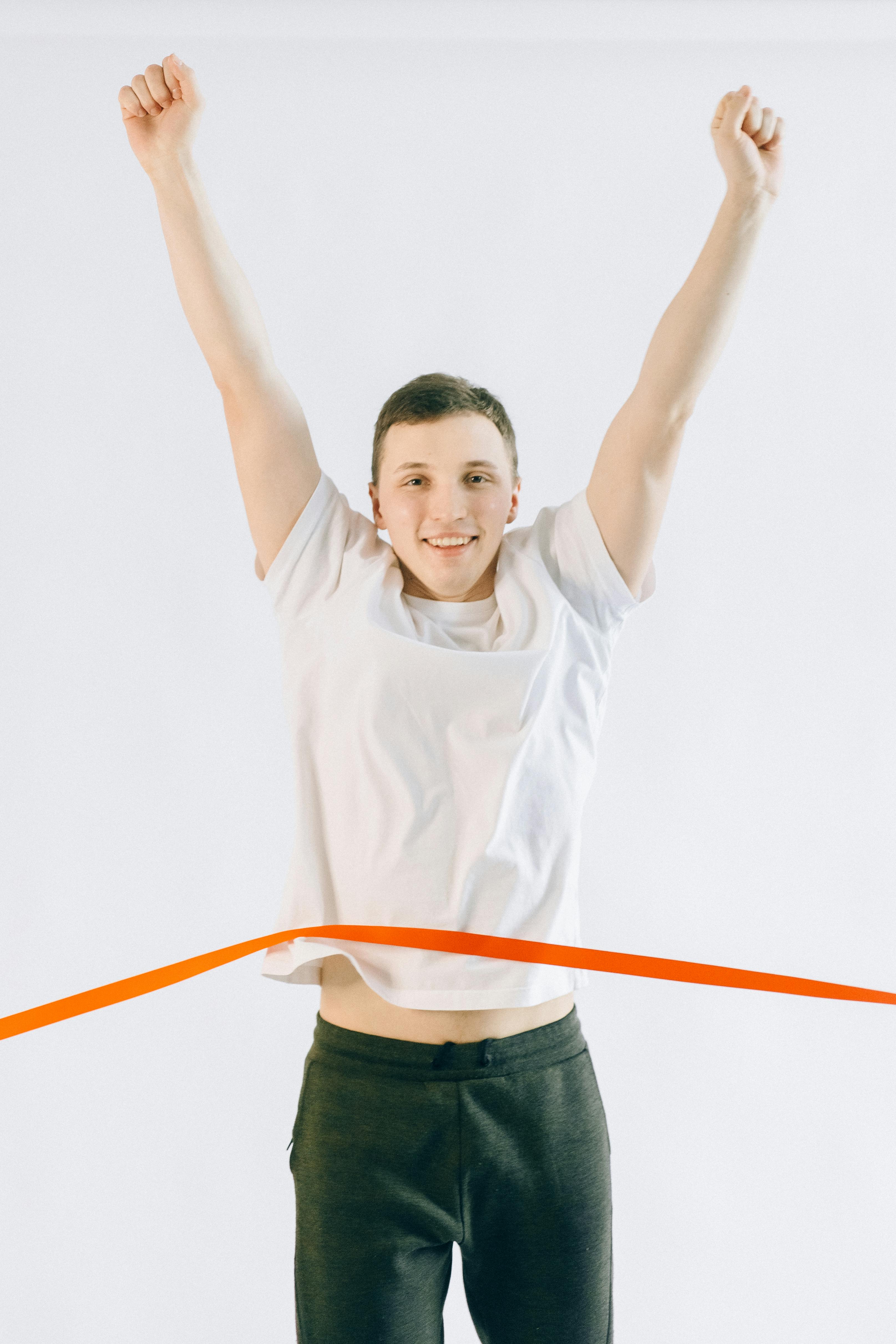 man in white crew neck t shirt and black denim shorts raising his hands