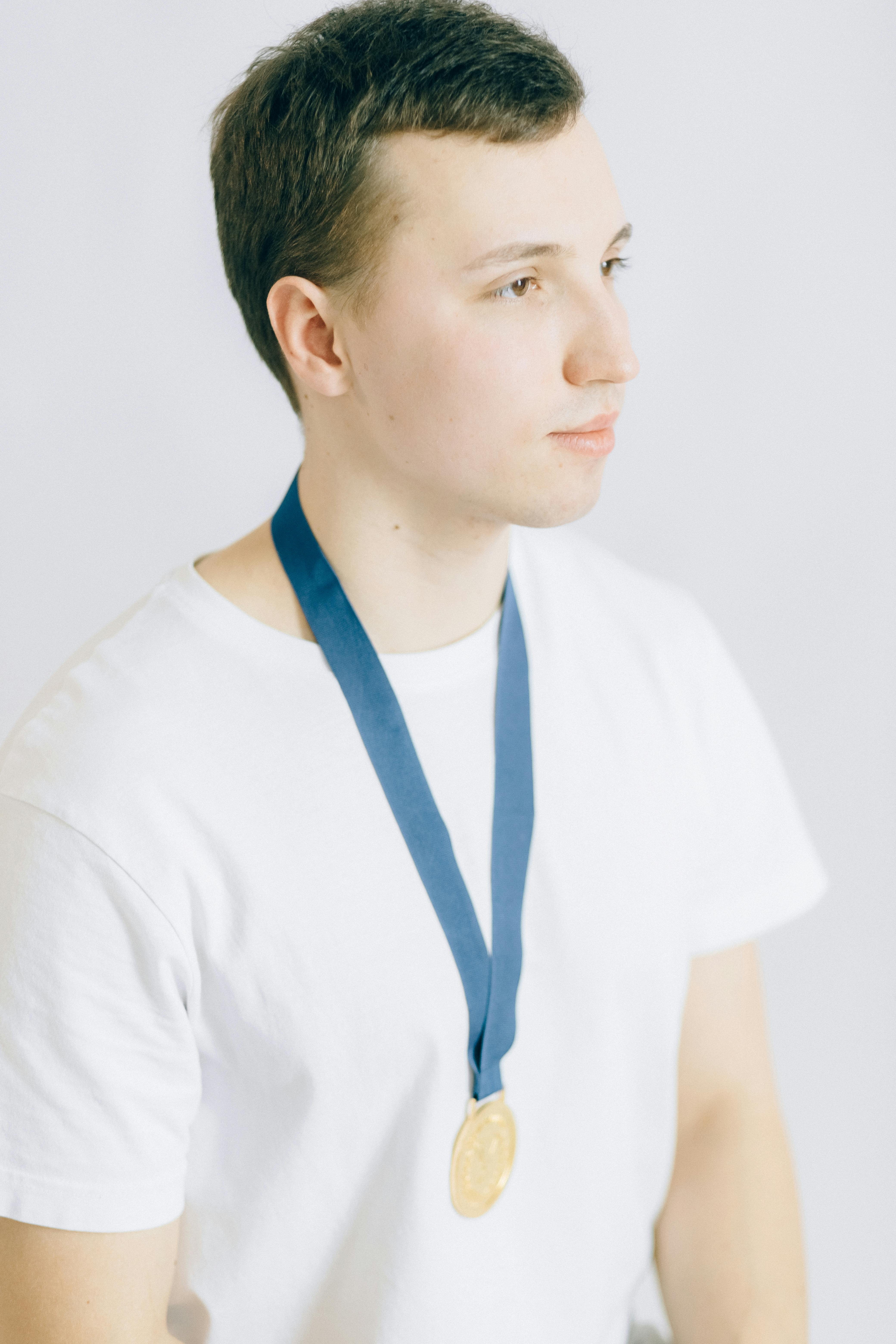 young man in white crew neck t shirt wearing a gold medal