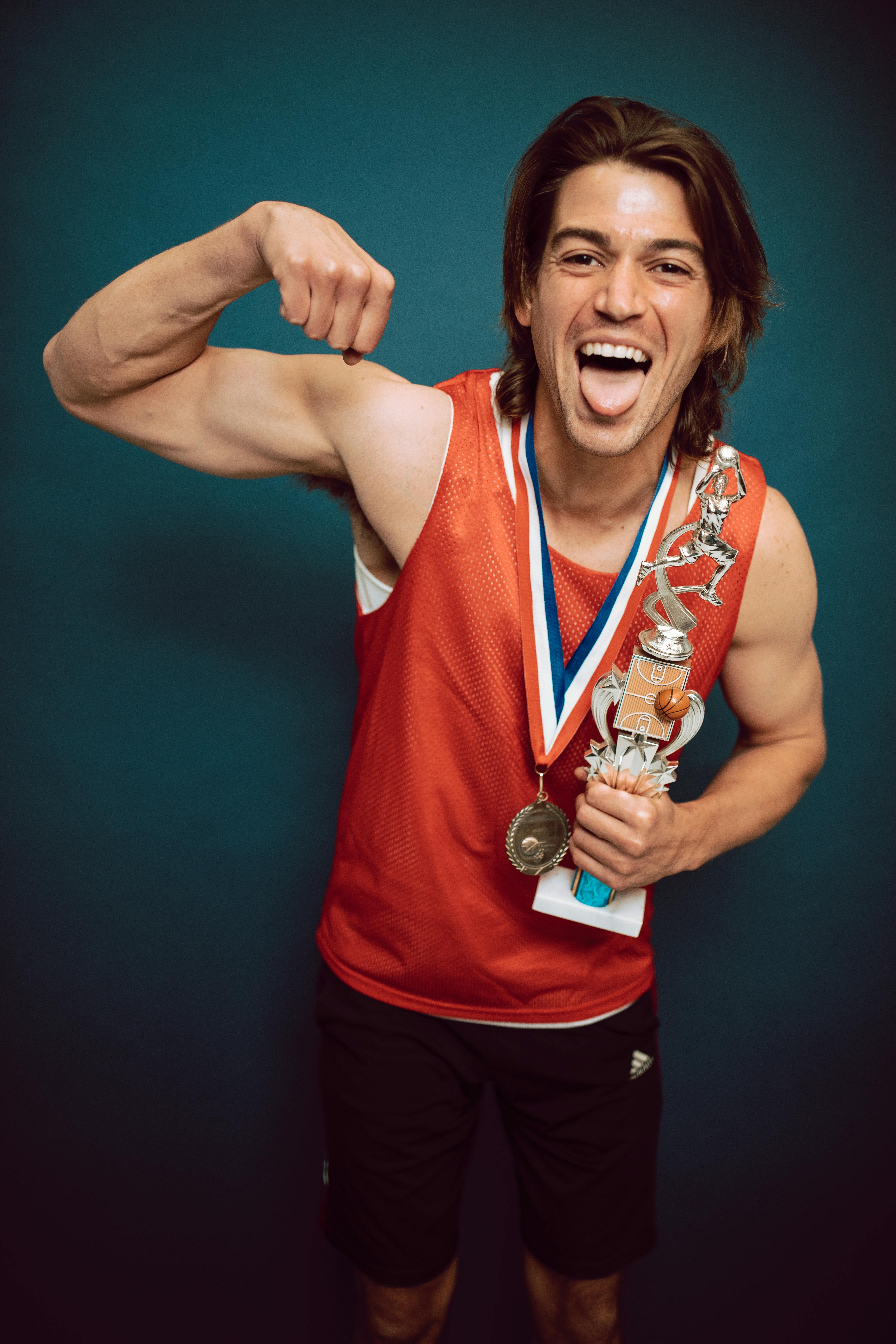 a man flexing his muscle while holding a trophy