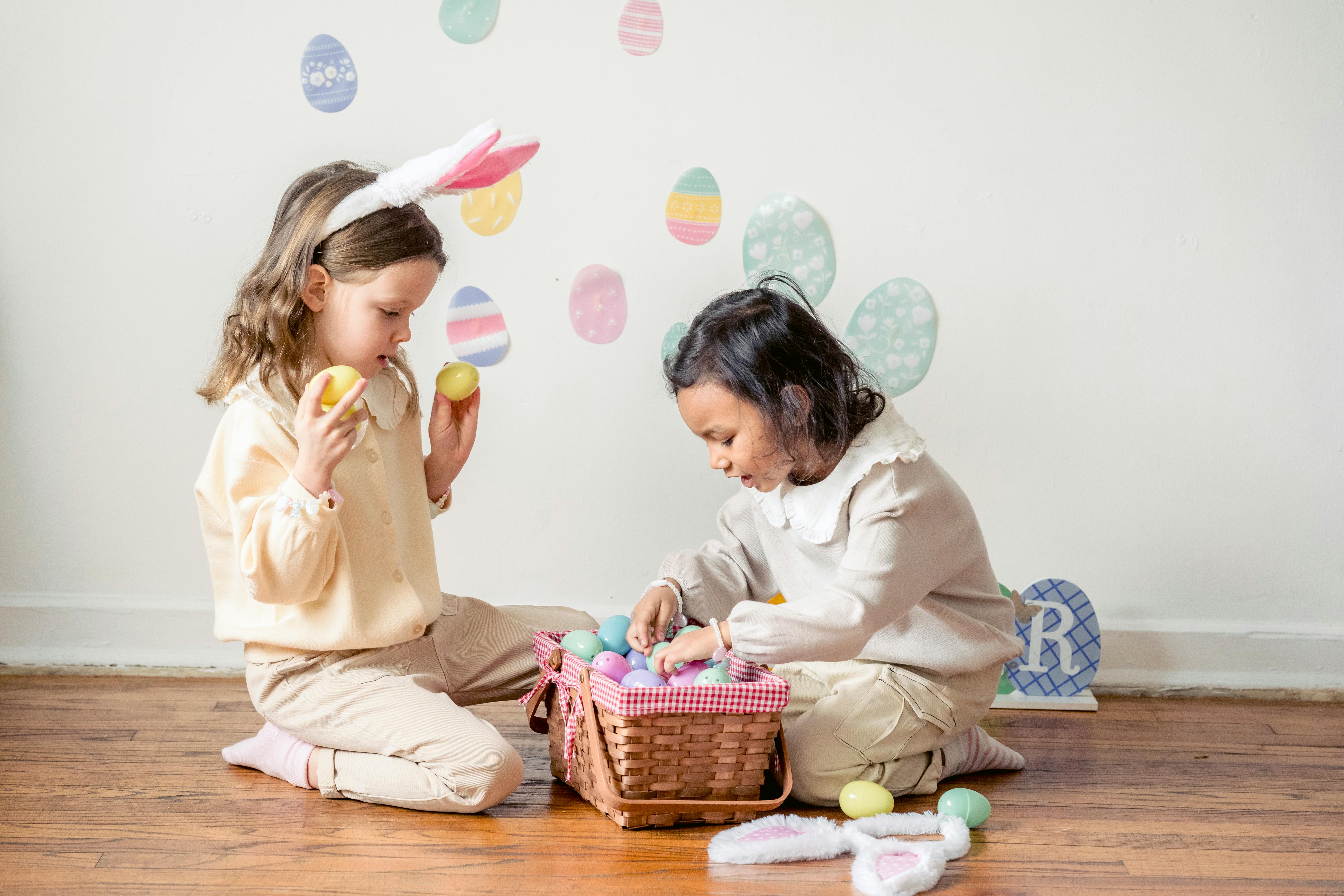 cute happy diverse children sitting on floor and playing together with multicolored egg toys