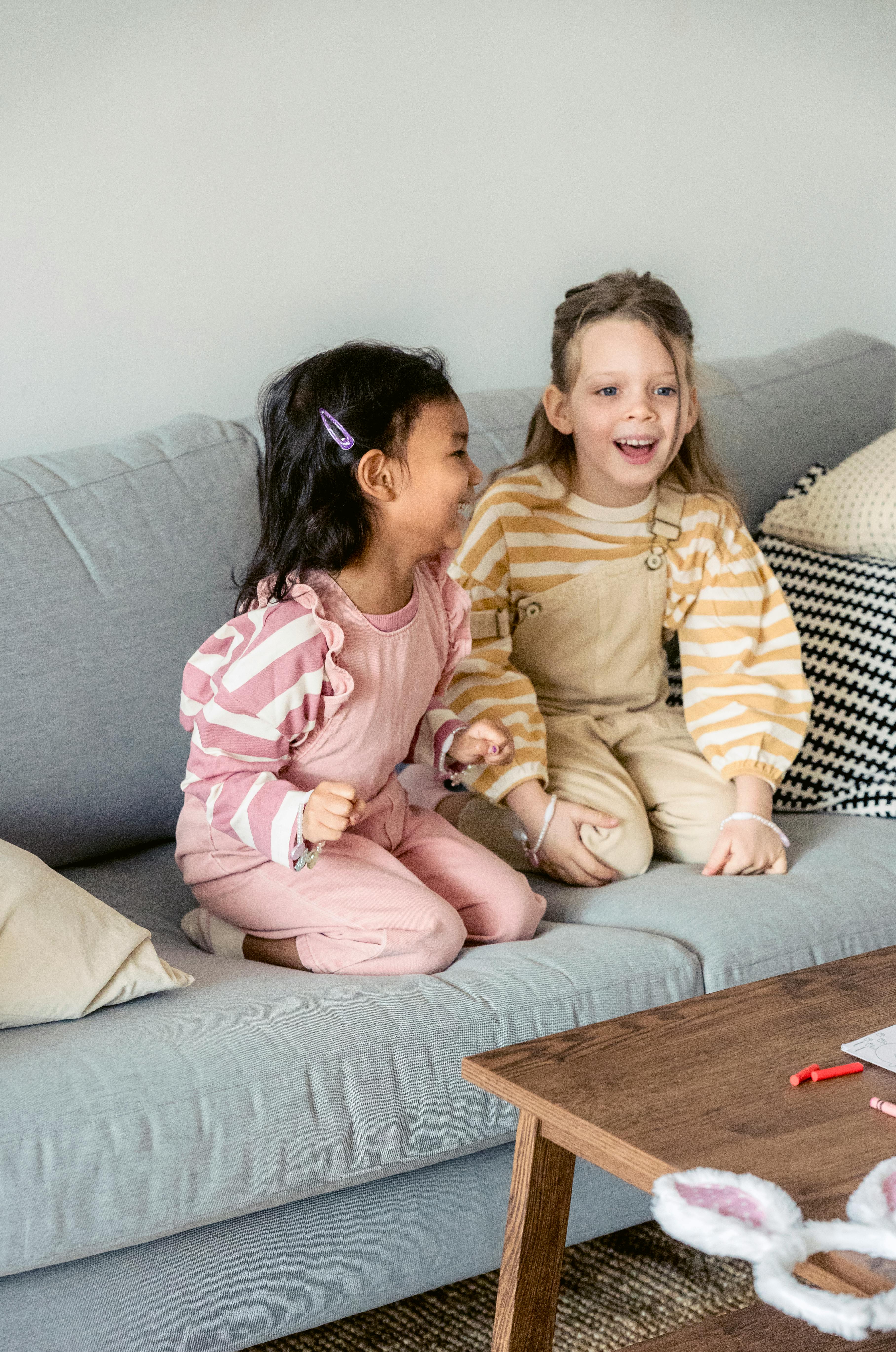 playful diverse girls laughing on sofa