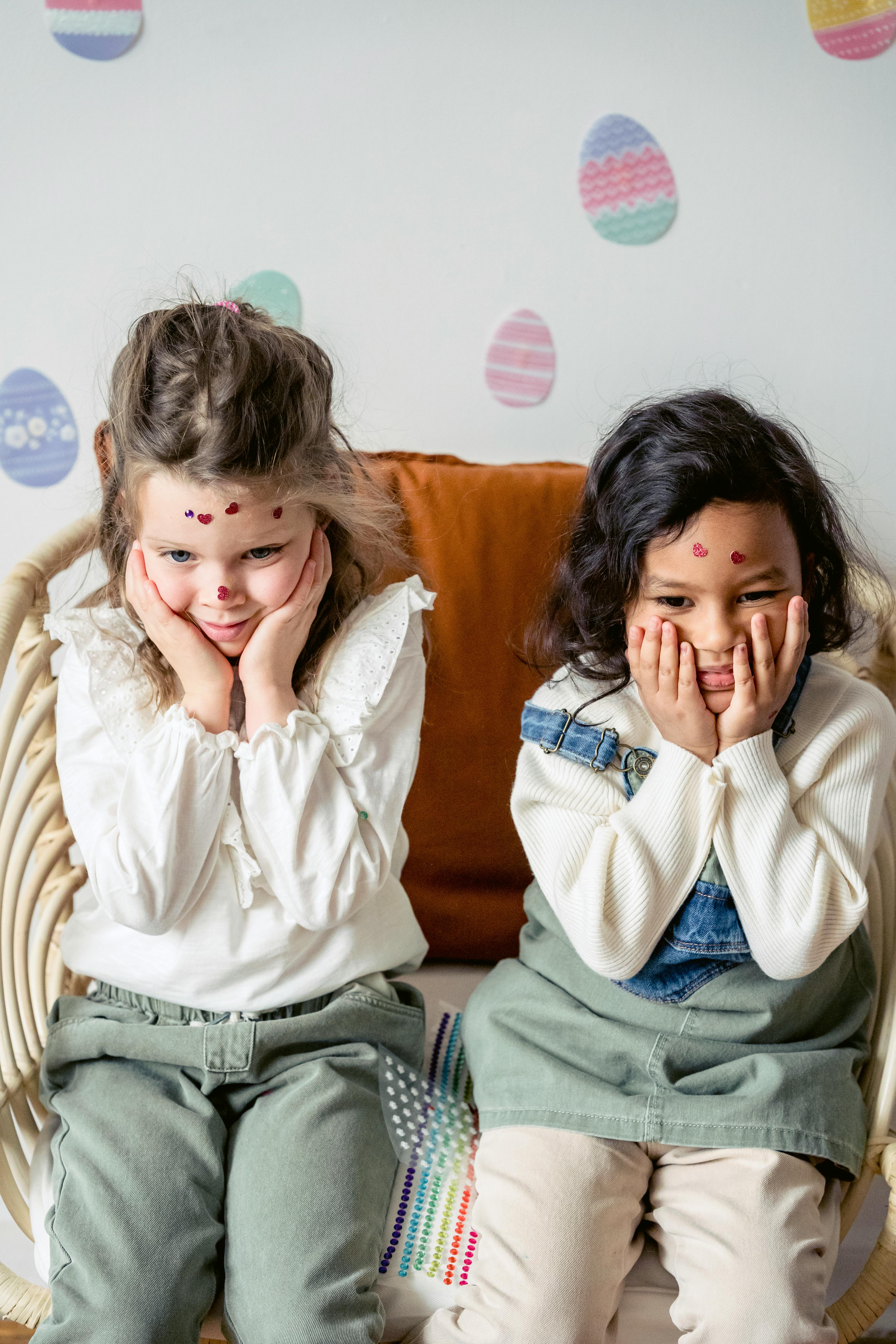 calm diverse girls with stickers on faces during easter celebration