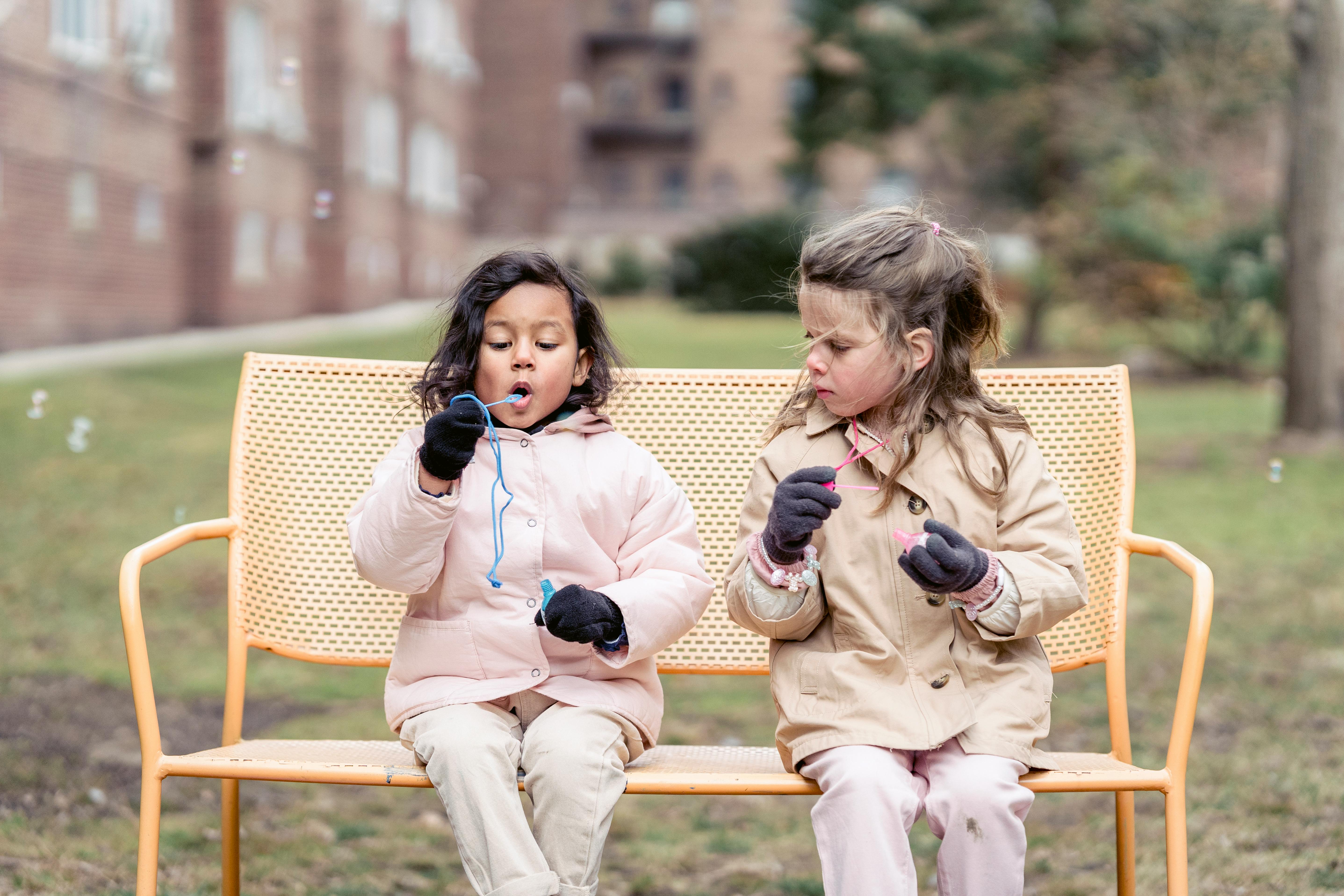 cheerful diverse girls blowing bubbles in autumn park