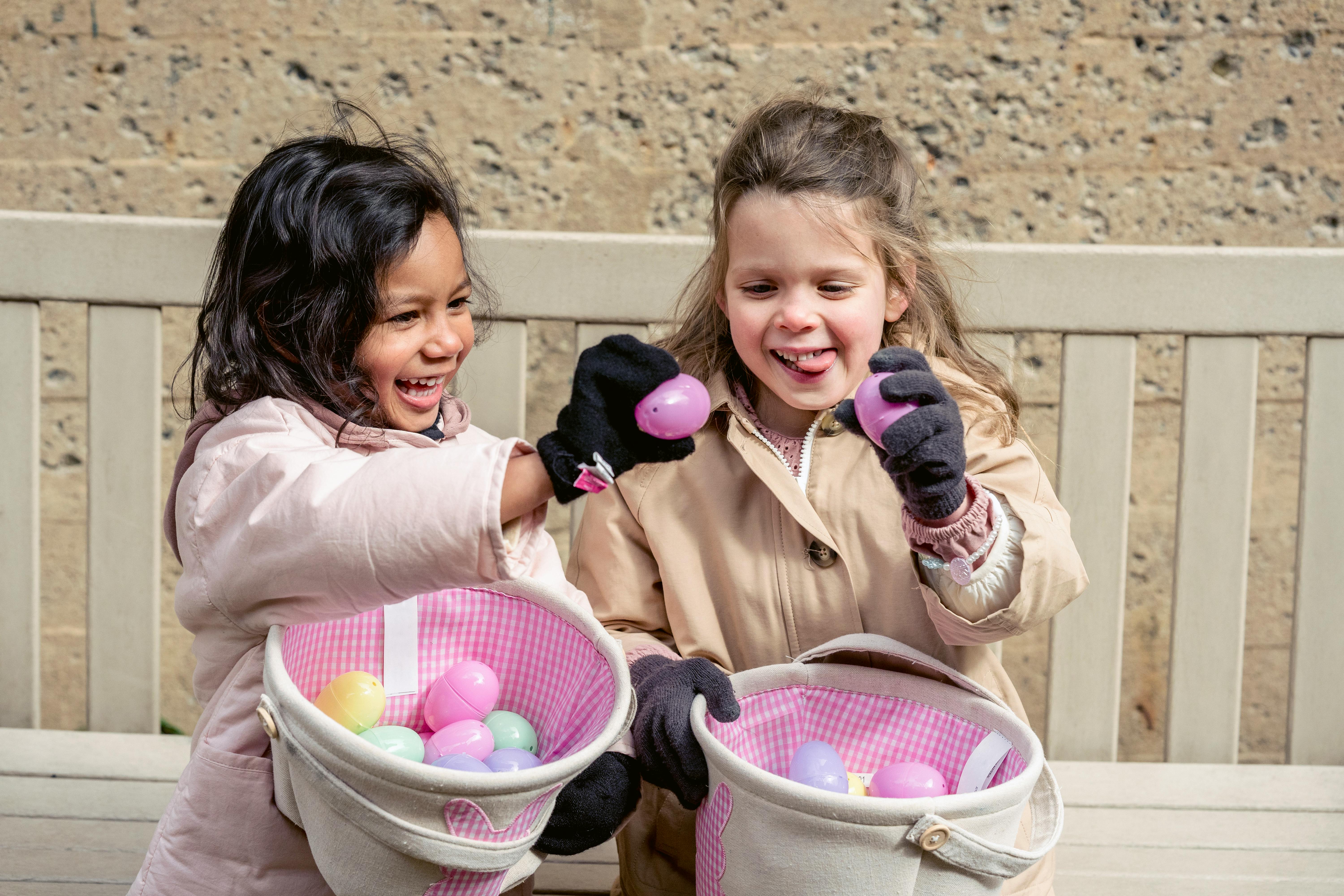 happy diverse girls with baskets of decorative eggs