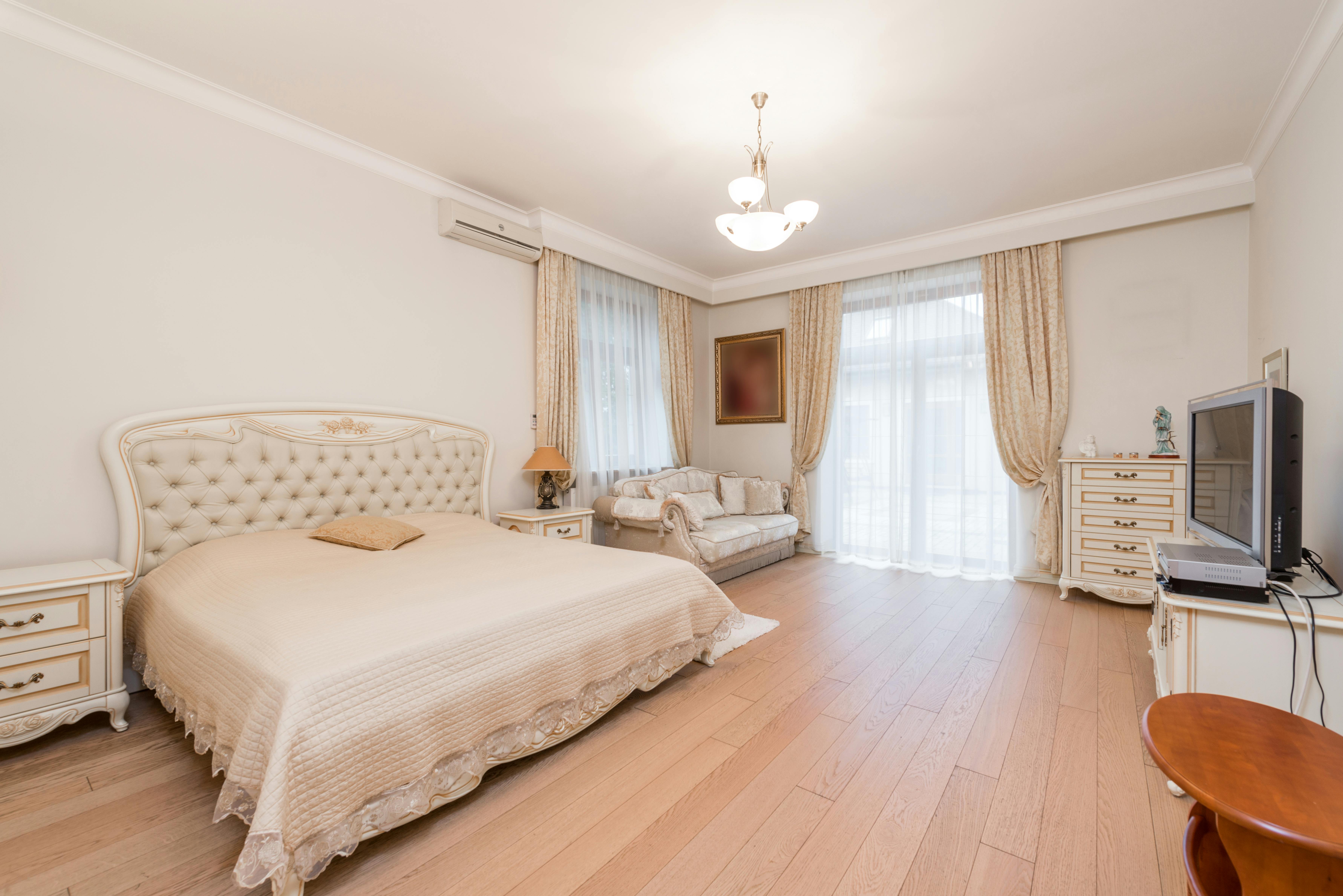 bedroom interior with bed near sofa and tv on cupboard