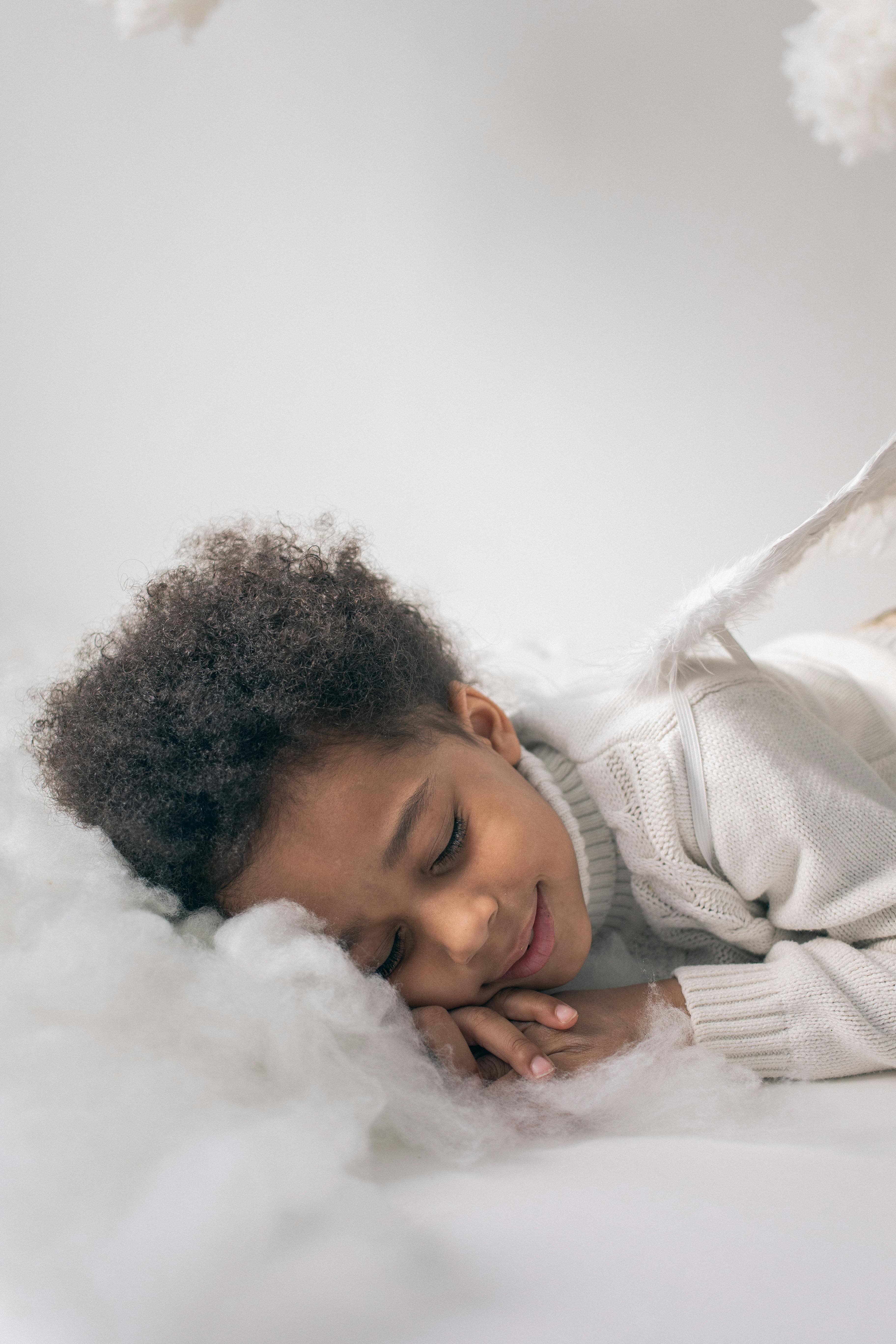 cute black boy in angel costume sleeping on cotton cloud