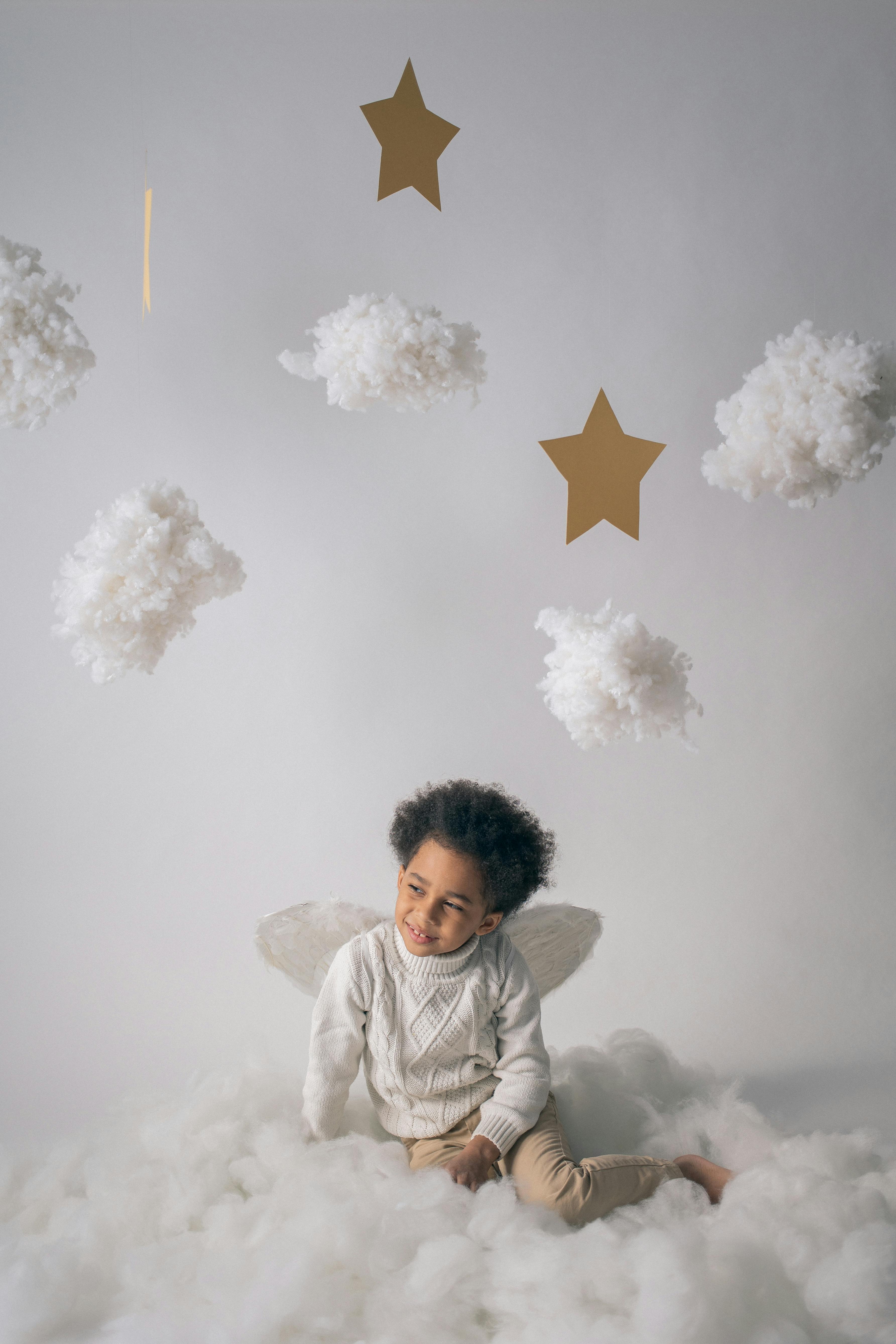 cute black boy in wings near hanging decorations