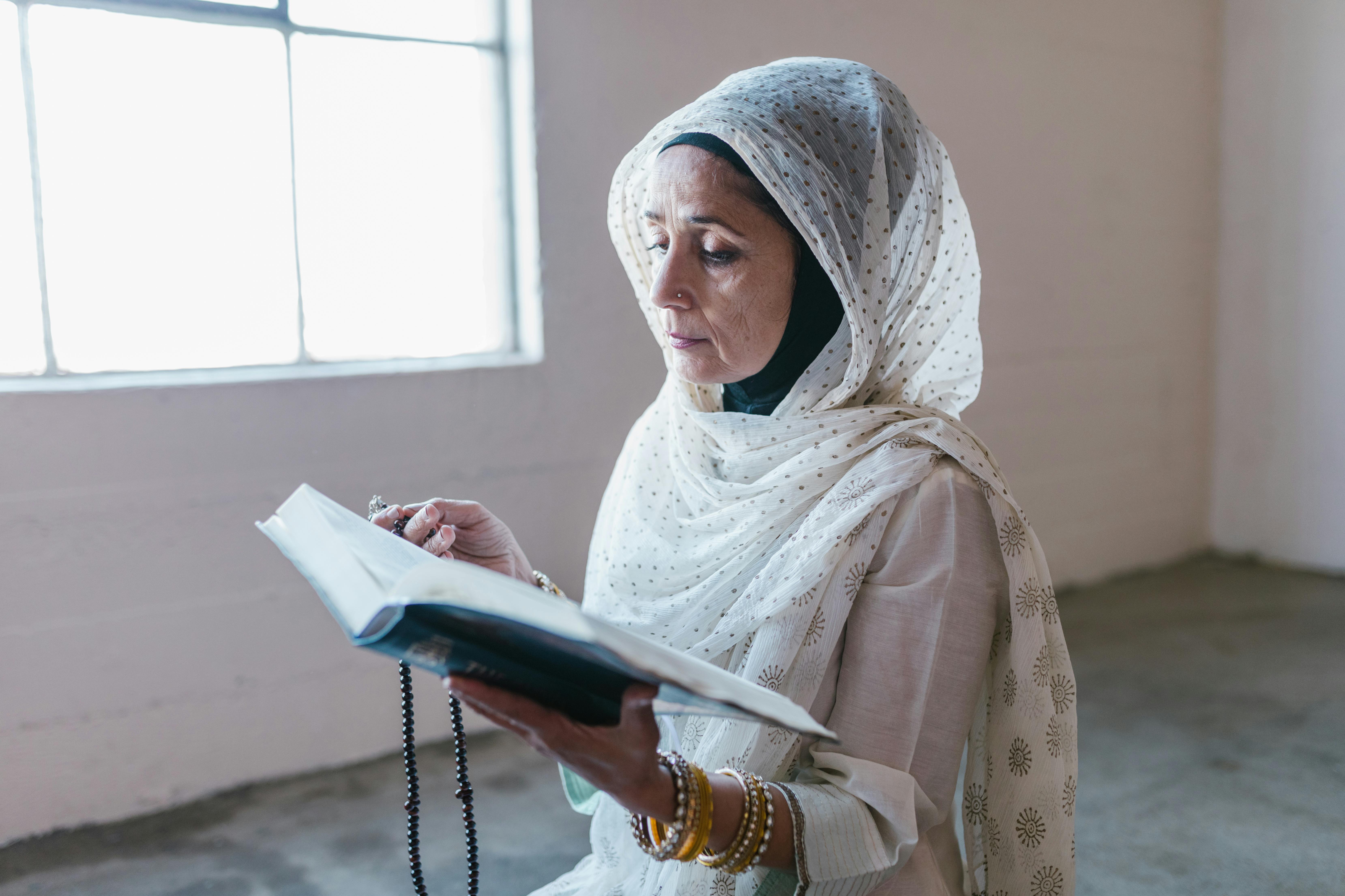 woman in white hijab holding book