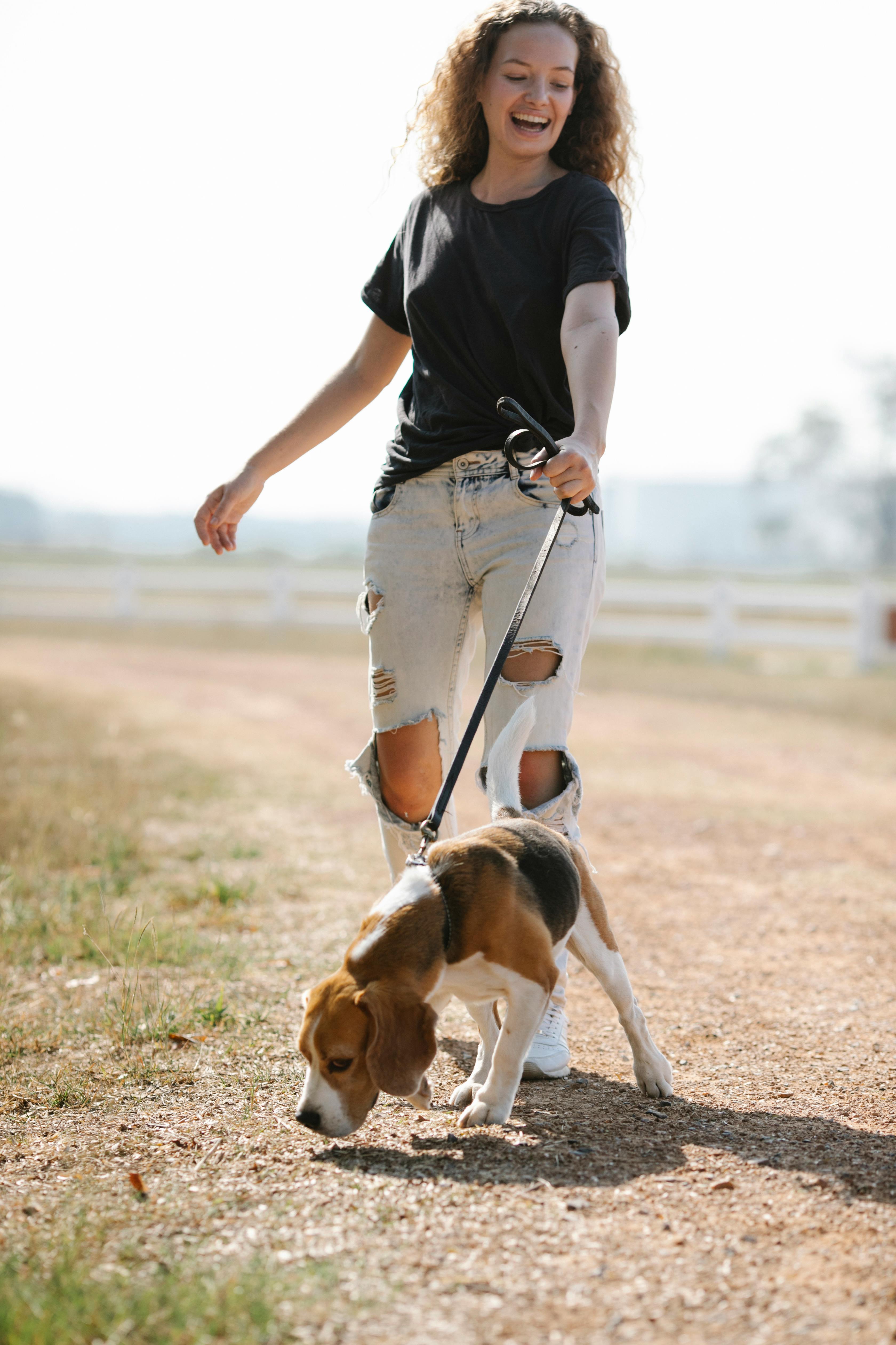 happy woman walking with dog sniffing ground