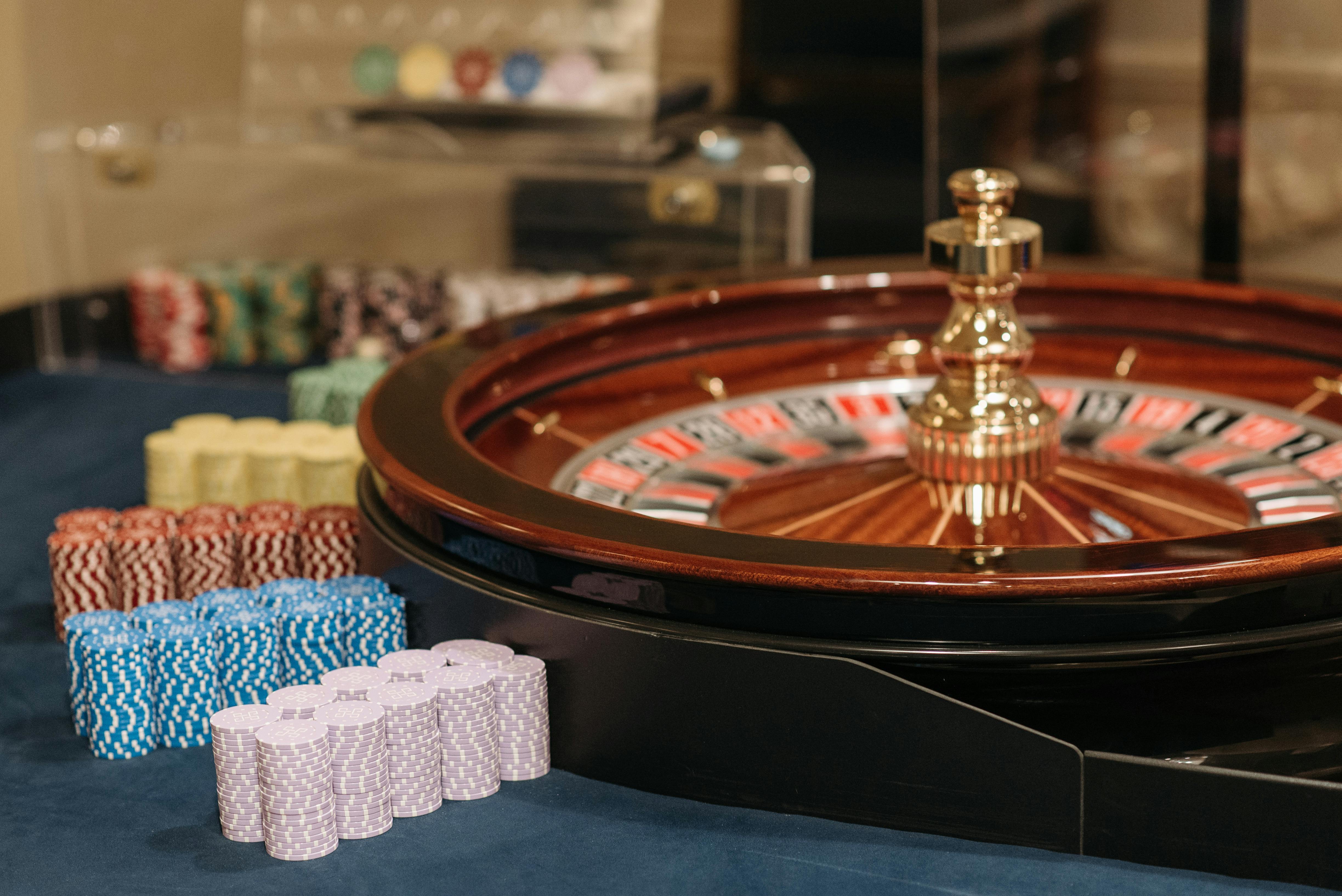 close up photo of stacked poker chips beside casino roulette