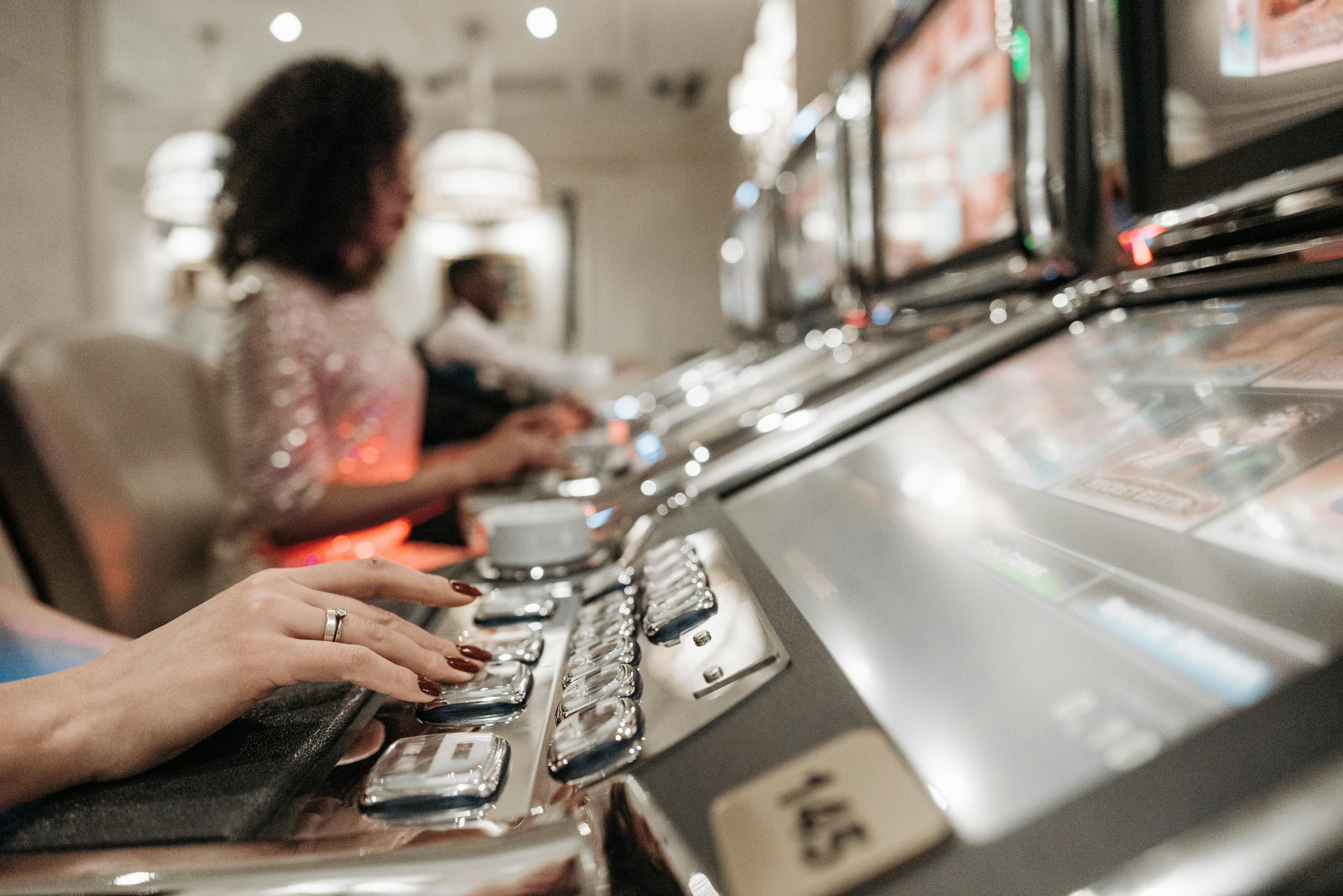 a person with manicured nails pressing buttons on a slot machine