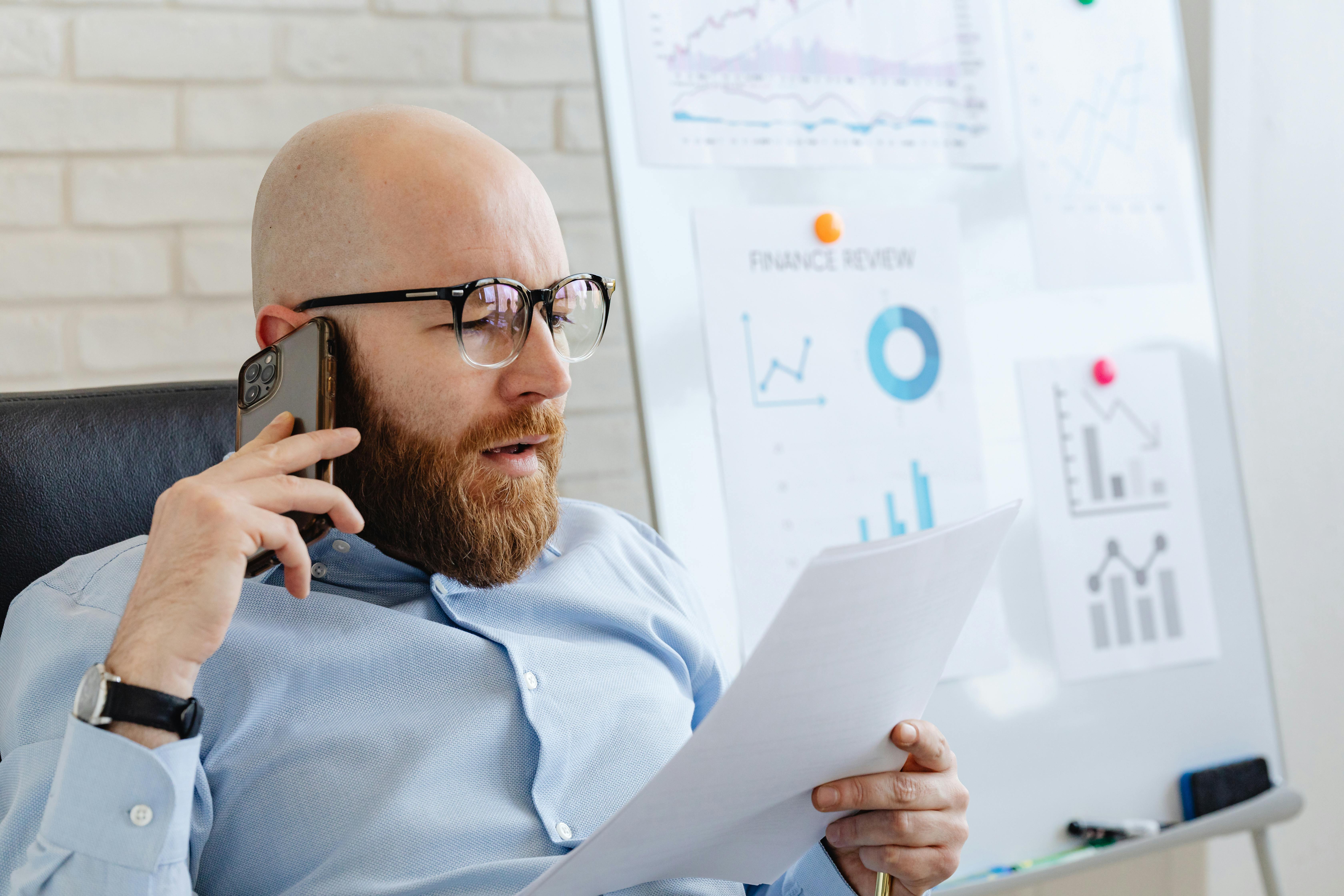 a man talking on the phone while looking at documents