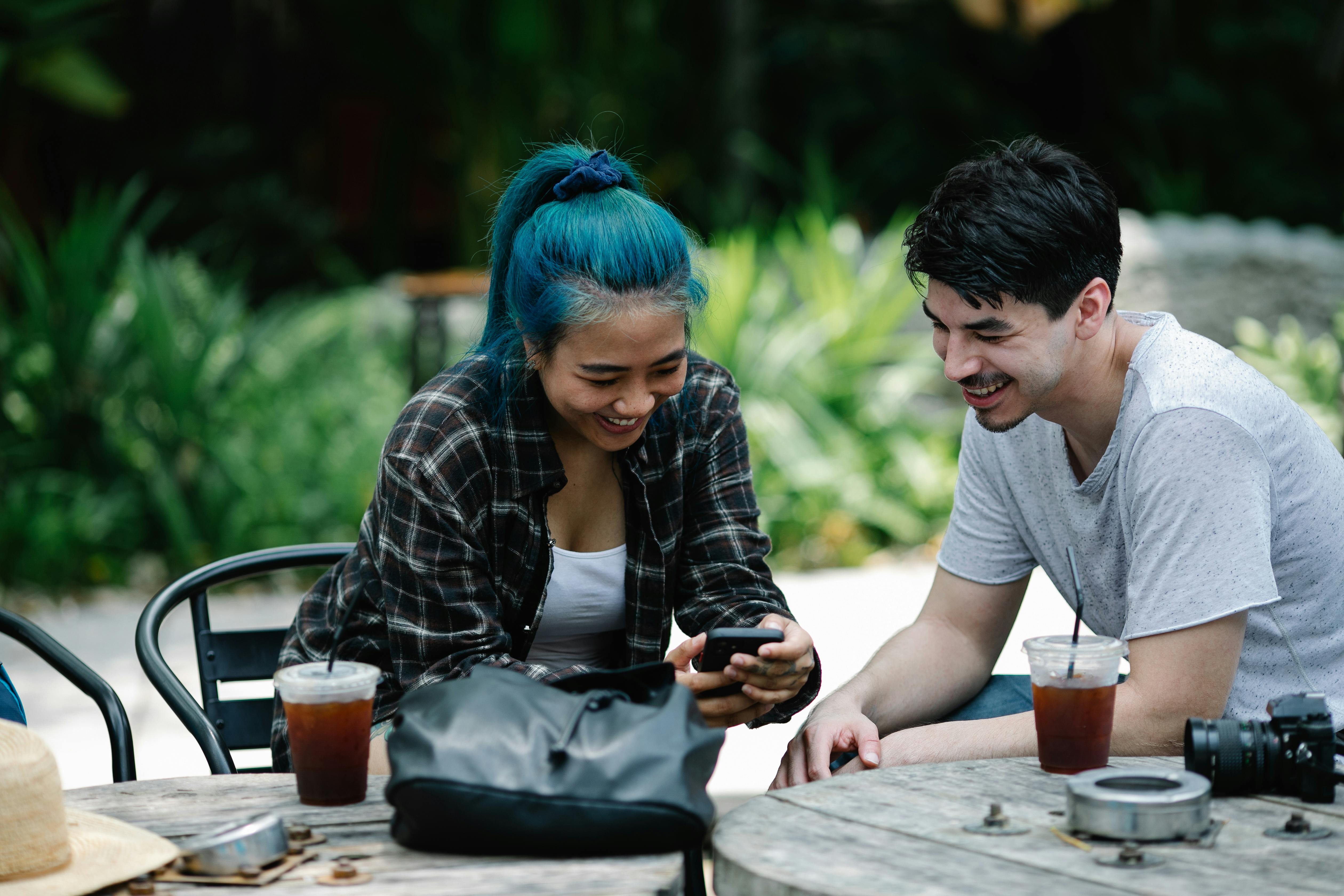 cheerful multiethnic couple browsing smartphone in cafe