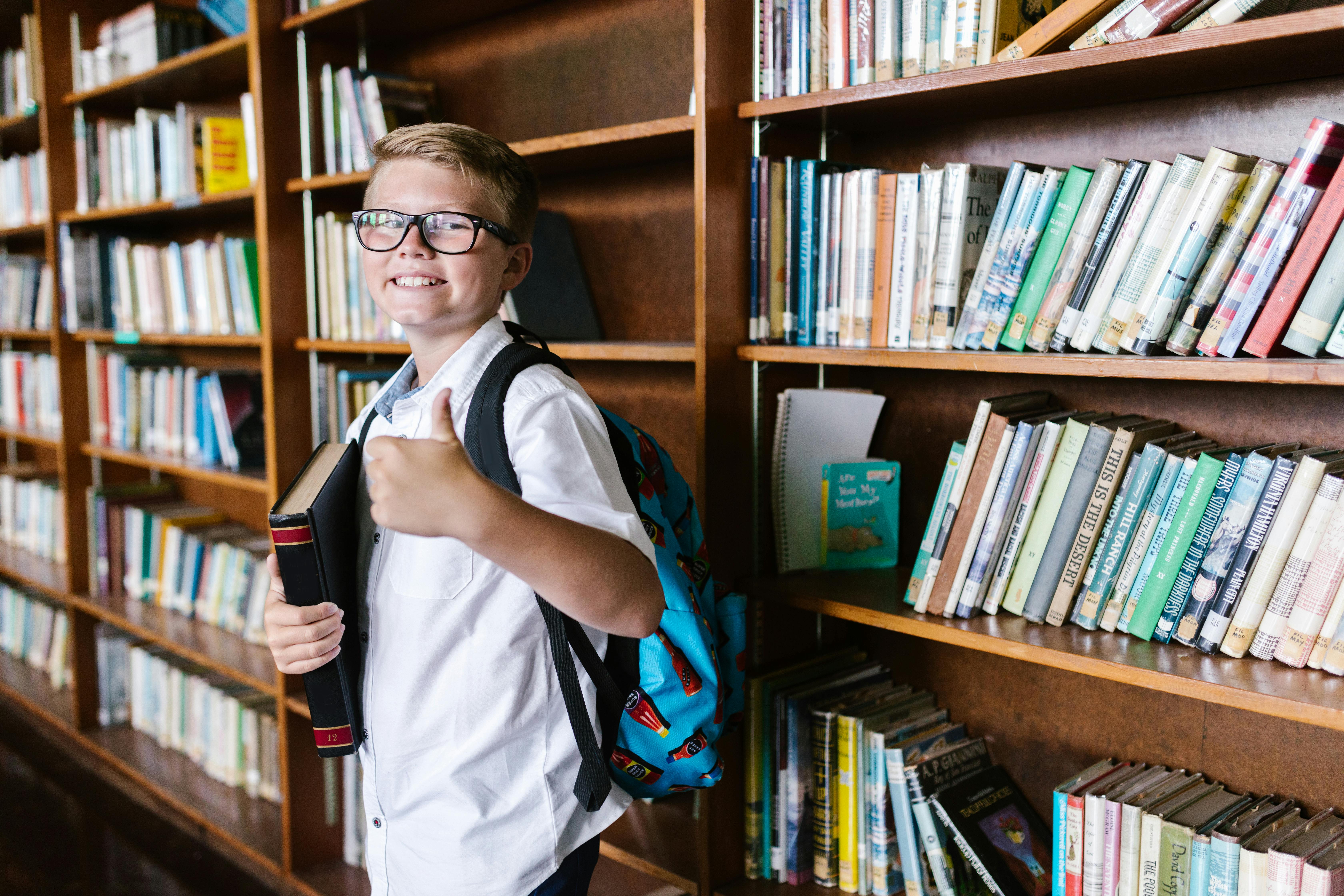 a boy in the library with his thumbs up