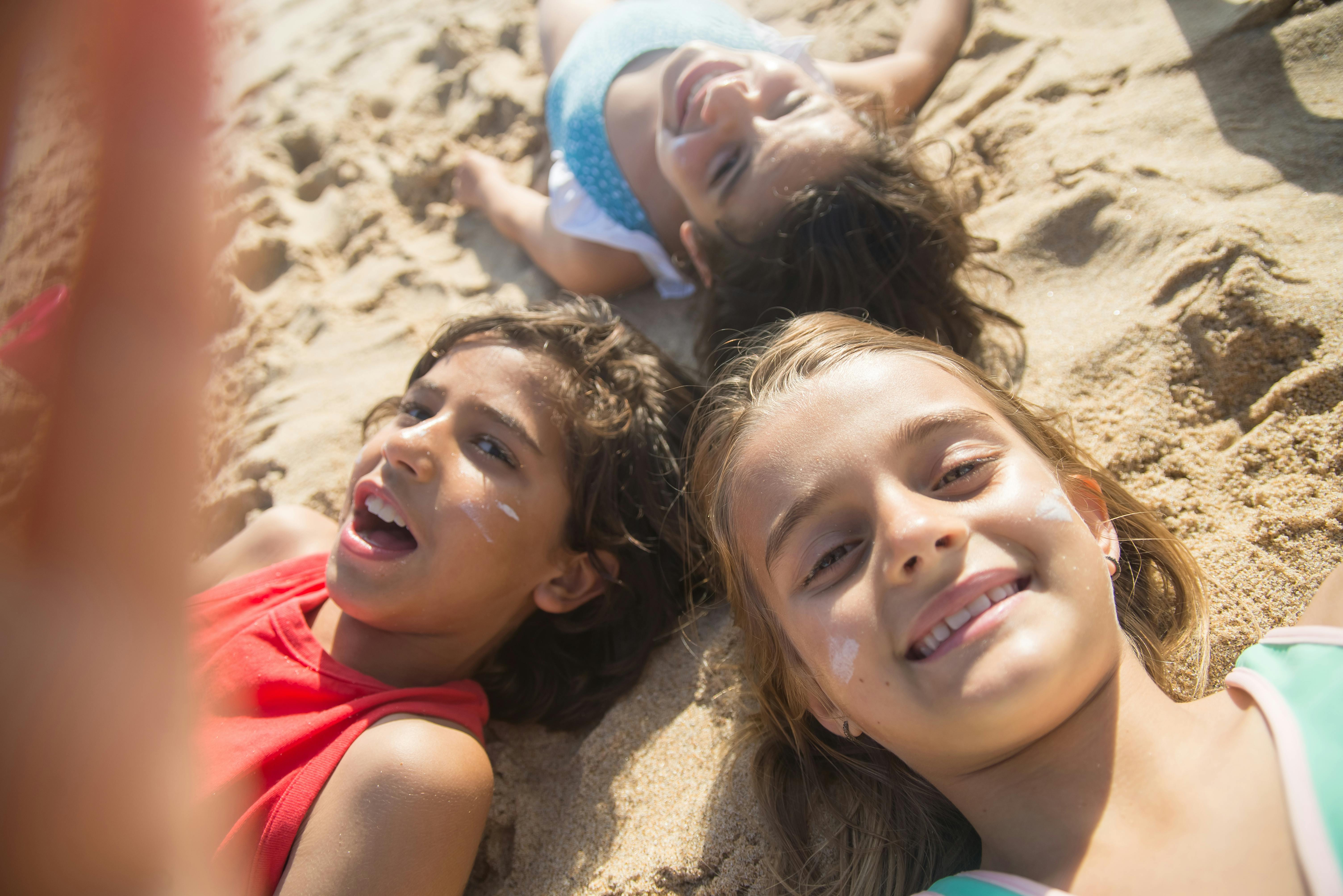 children lying on brown sand