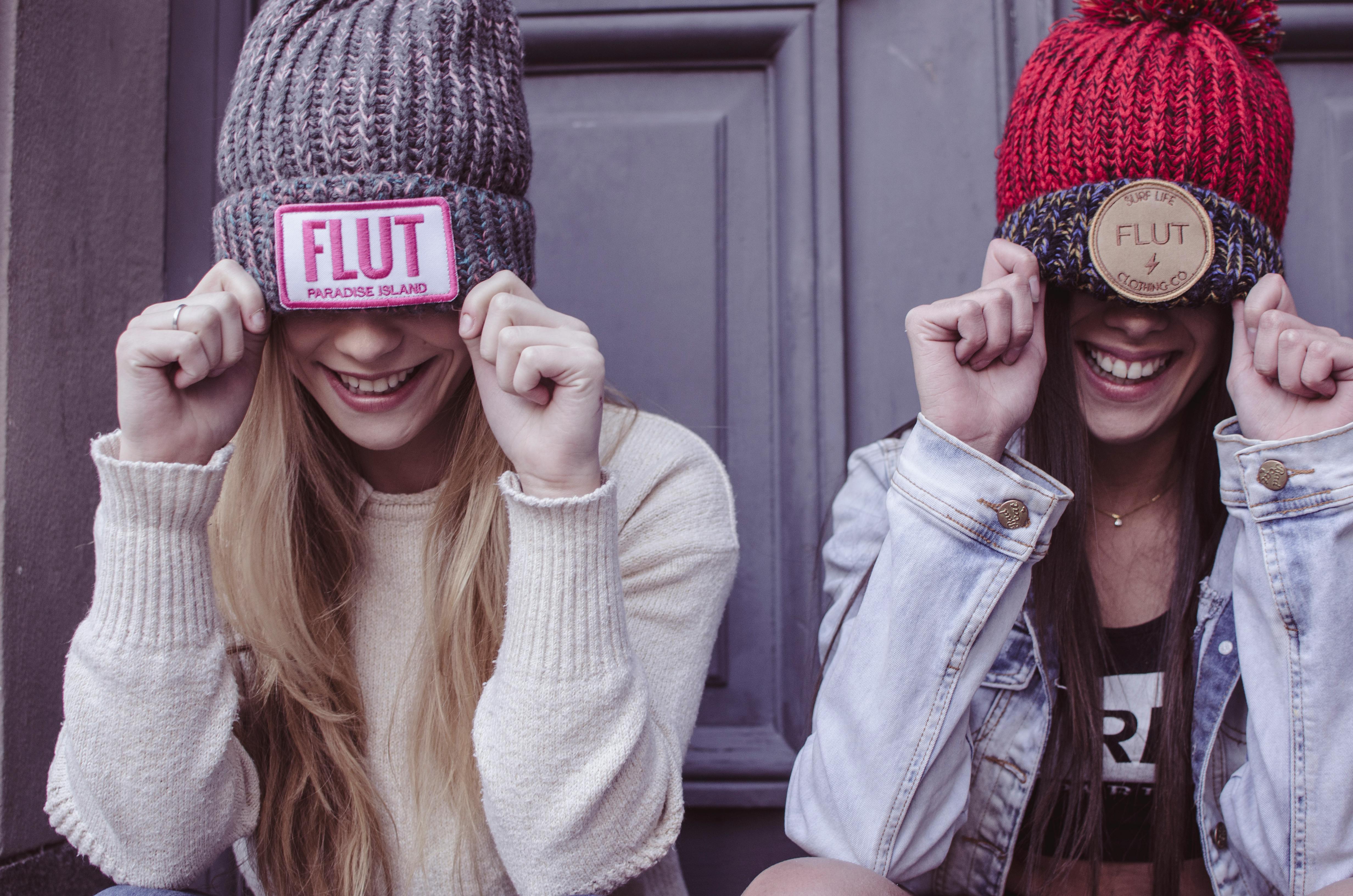 two women s gray and red flut knit caps