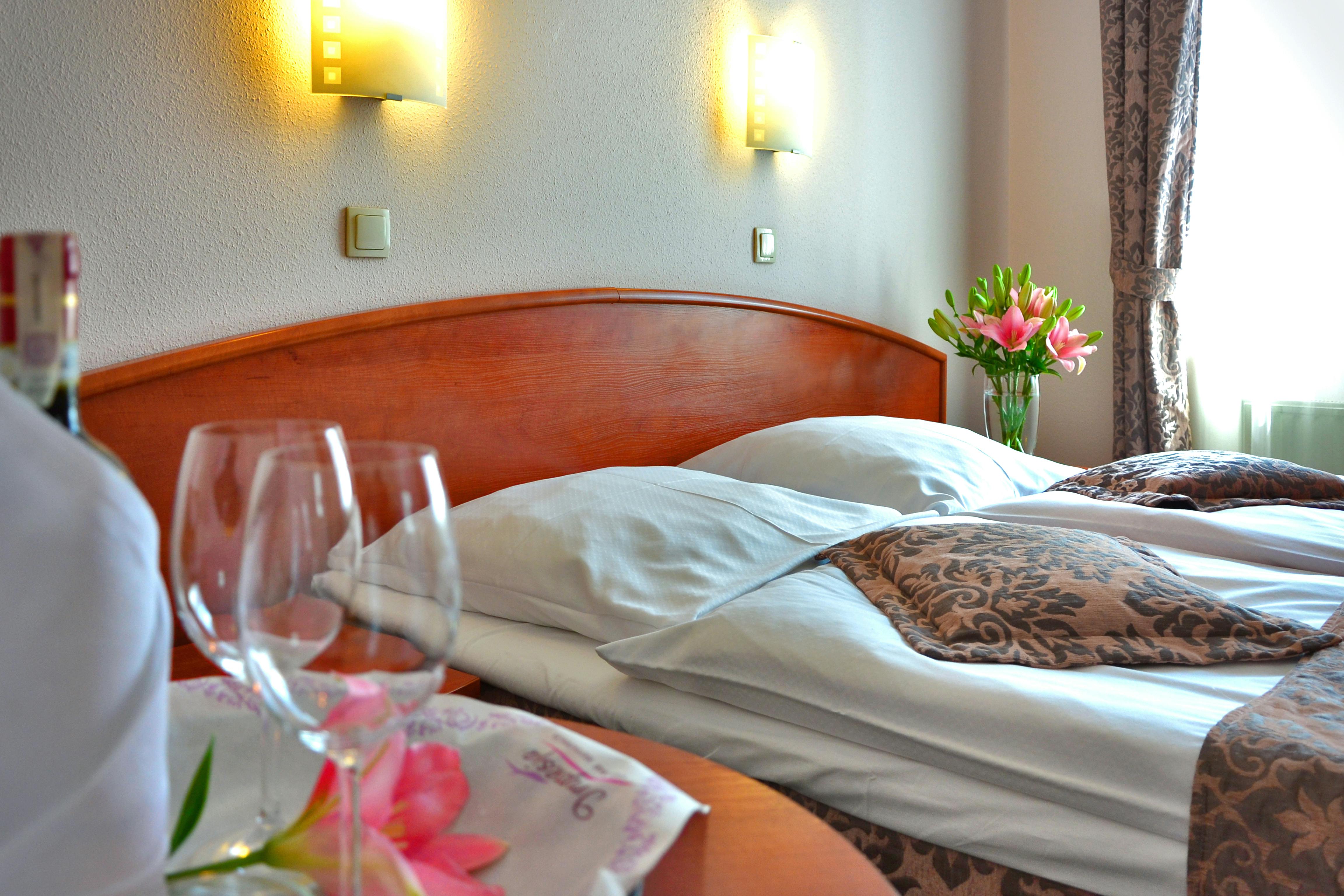 clear wine glass on brown wooden table top near bed