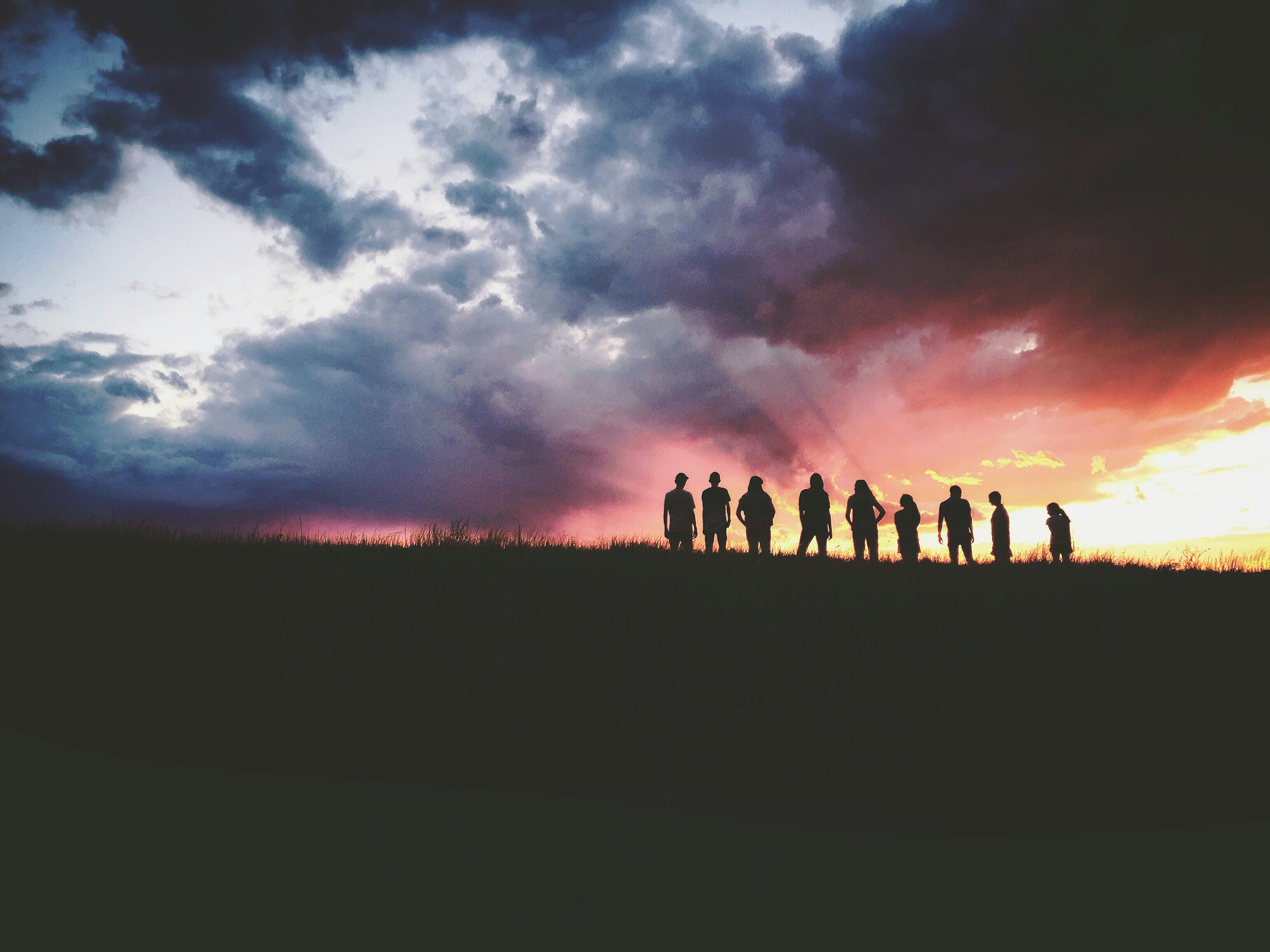 silhouette of nine persons standing on the hill