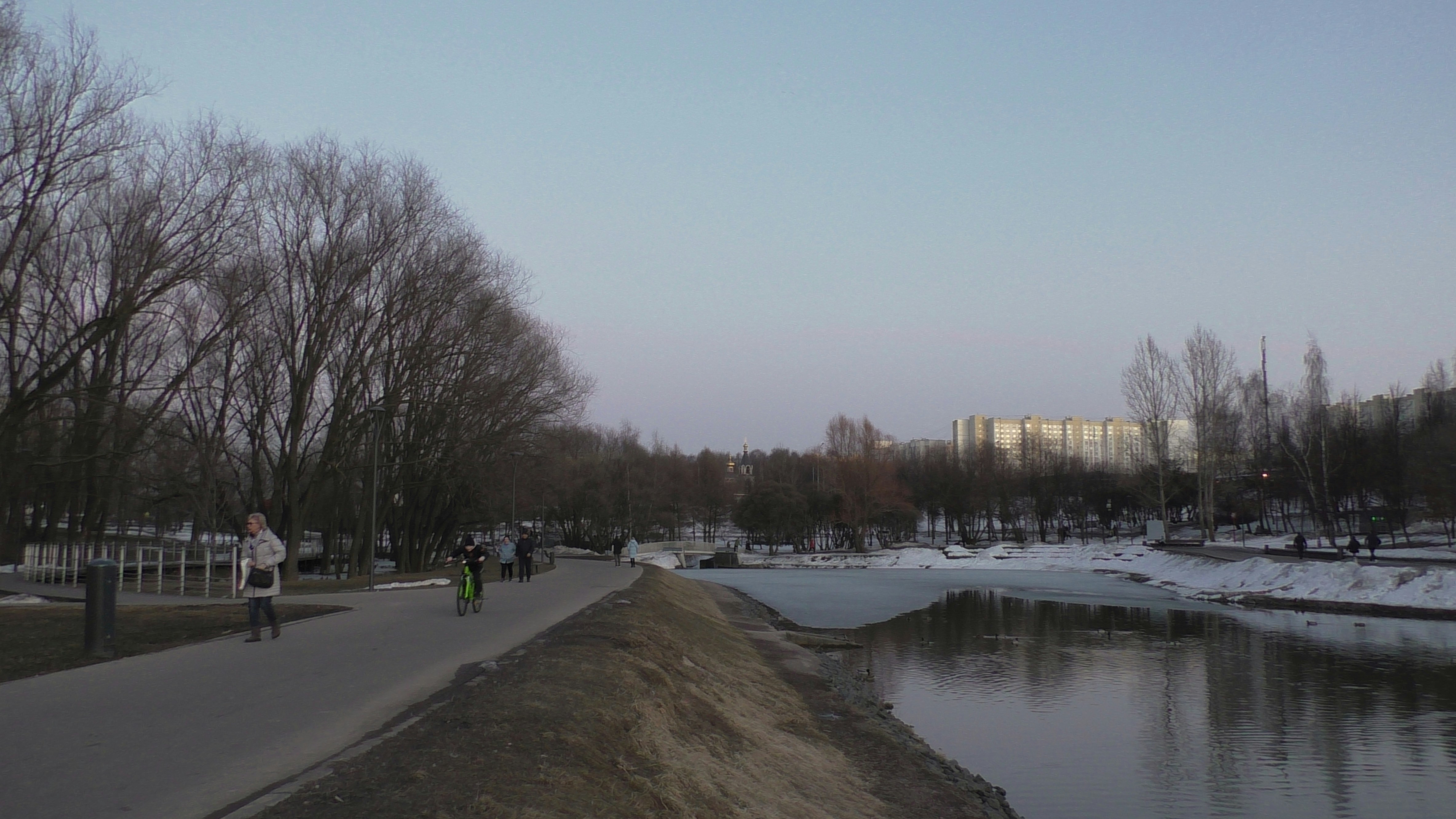 a group of people riding bikes down a street next to a river