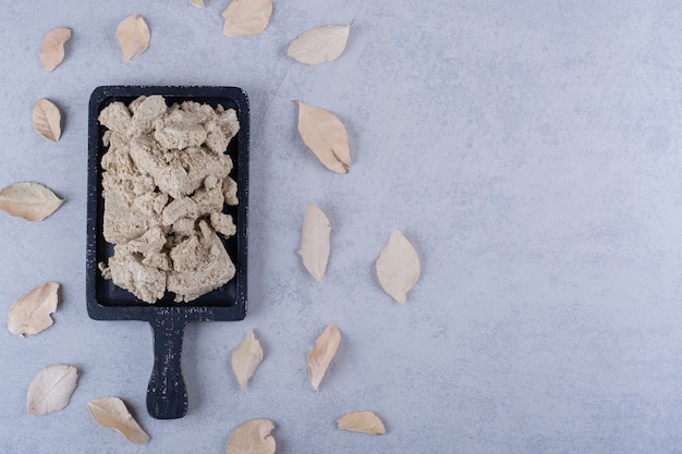 Free photo tasty sunflower halva on black wooden board with dry leaves.