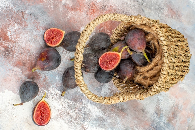 Free photo top view delicious figs scattered from basket on nude background