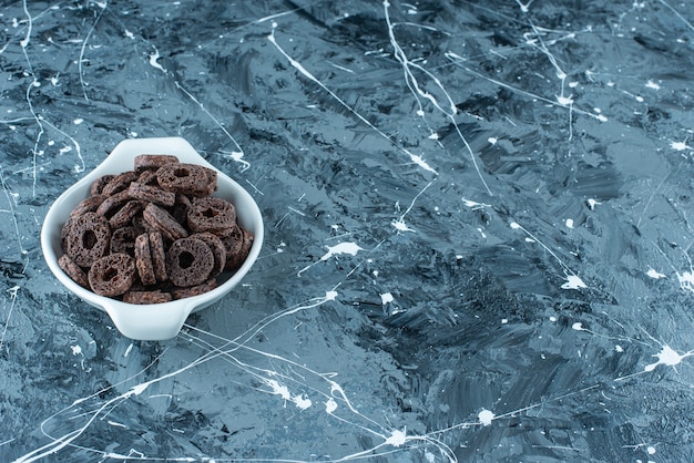 Free photo chocolate coated corn ring in a bowl, on the marble table.