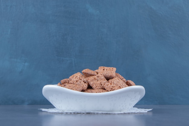 Free photo chocolate corn pads in bowl on a coaster,, on the blue table.