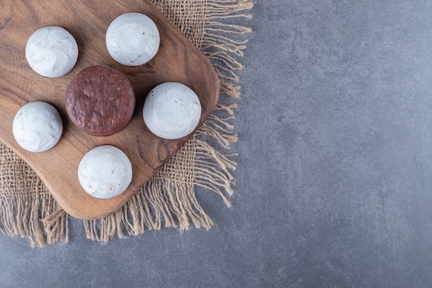 Free photo chocolate cake pops and biscuit on board on the towel on marble table.