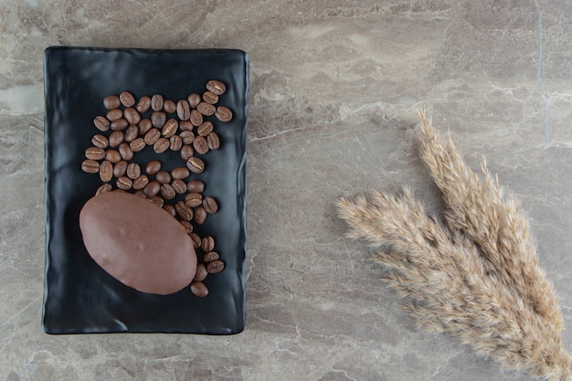 Free photo chocolate cupcake on black plate with coffee beans