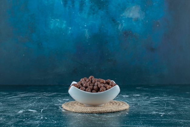 Free photo corn balls in a bowl on a trivet , on the blue background. high quality photo