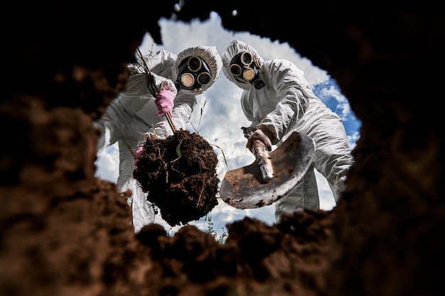 Free photo ecologists digging pit by shovel and planting tree in polluted area