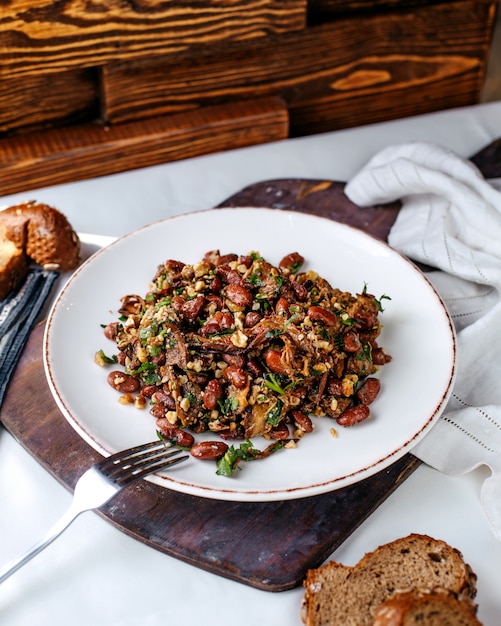 Free photo front view fried beans along with greens inside white plate on the brown wooden desk and surface