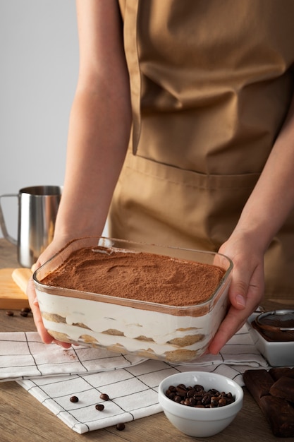 Free photo high angle cook holding tiramisu tray