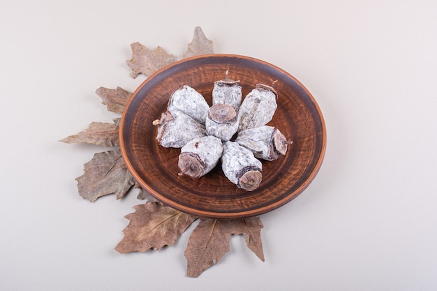 Free photo plate of dried persimmons and dry leaves on white background. high quality photo