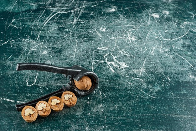 Free photo shelled walnuts with nut cracking tool on marble table.