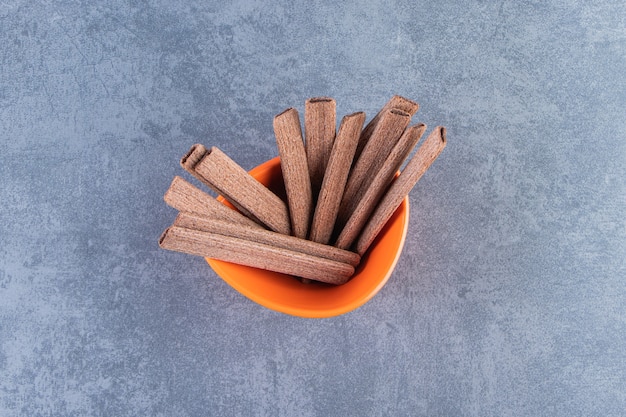 Free photo sweet chocolate wafer roll in a bowl, on the marble background.