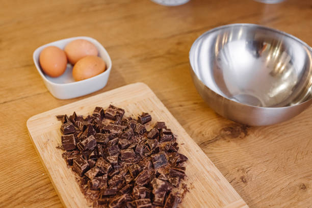 Prepping the ingredients before baking Chocolate chopped in small pieces, three eggs and an empty bowl. Baking. truffe noire ou acheter stock pictures, royalty-free photos & images