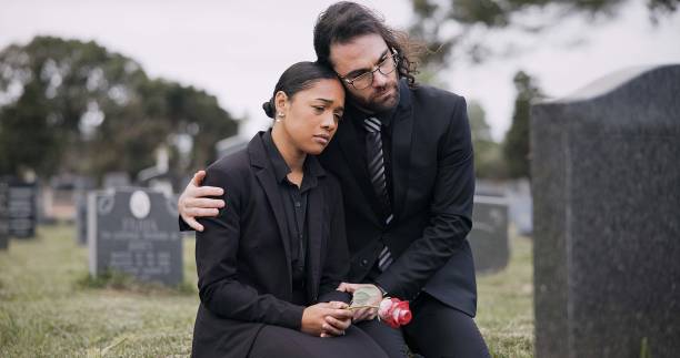 sad couple, rose and graveyard in loss, grief or mourning at funeral, tombstone or cemetery. man and woman hug with flower in depression, death or goodbye at memorial or burial service for loved one - boy friend stock-fotos und bilder